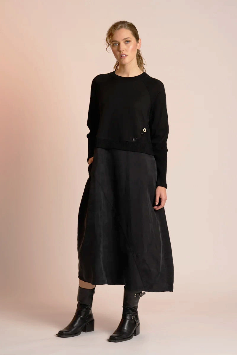 Woman wearing a black outfit with a long skirt on a beige background