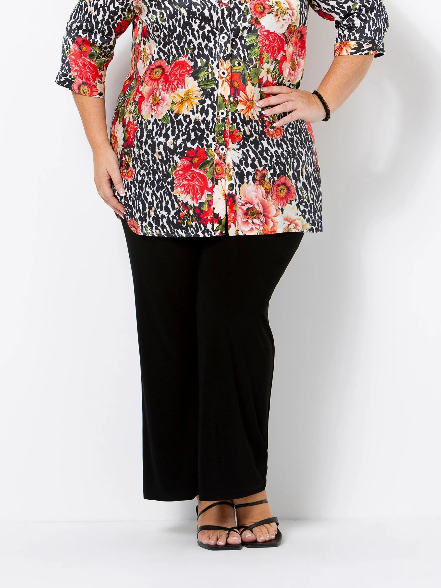 Person wearing a floral and leopard print top with black pants on a white background