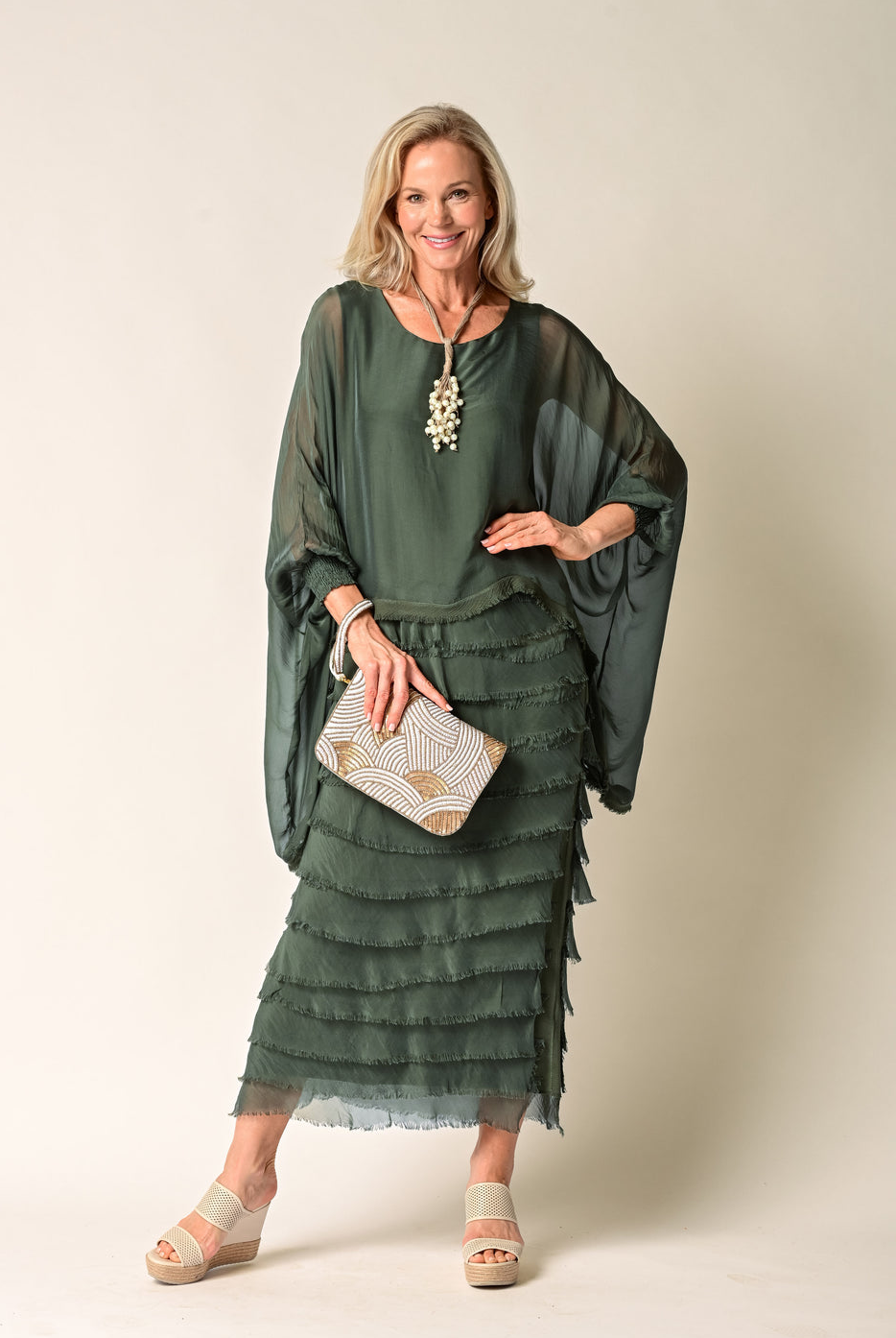 Woman wearing a green layered dress with a plain background
