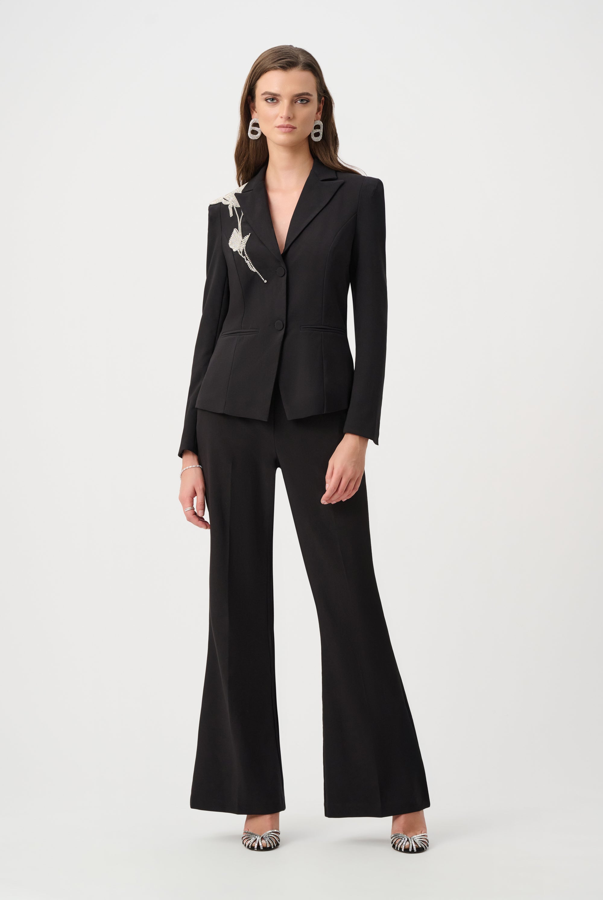 women wearing black blazer with rhinestone applique and black pants on white background