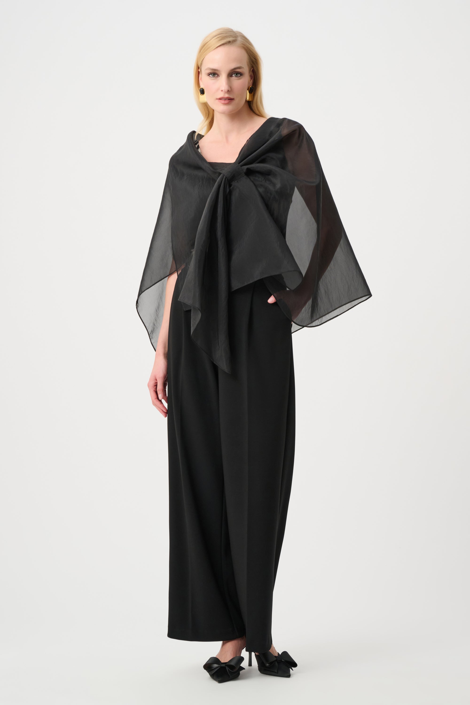 Woman wearing a black outfit with a large black scarf on a white background