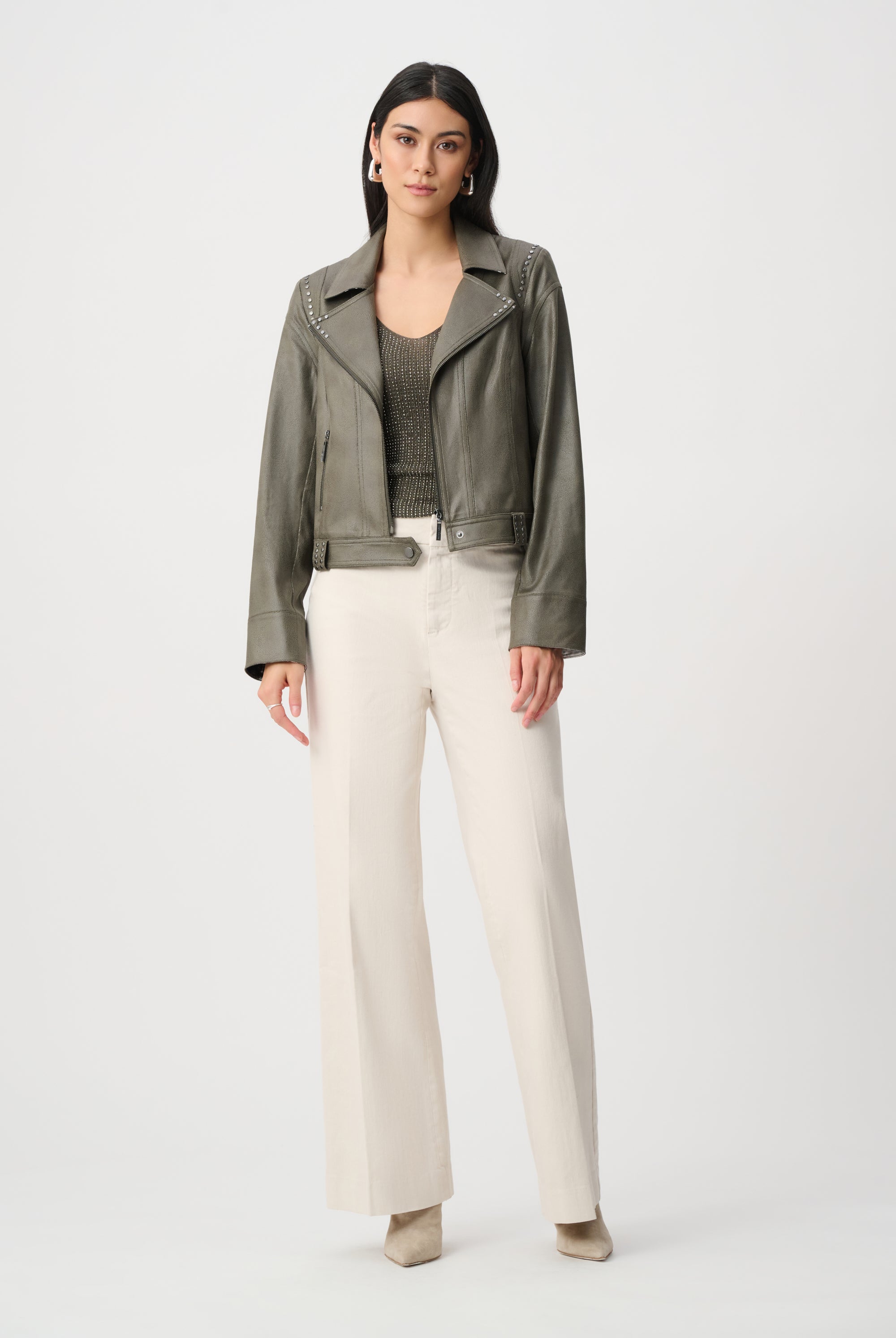 Woman wearing a green jacket and white pants on a white background