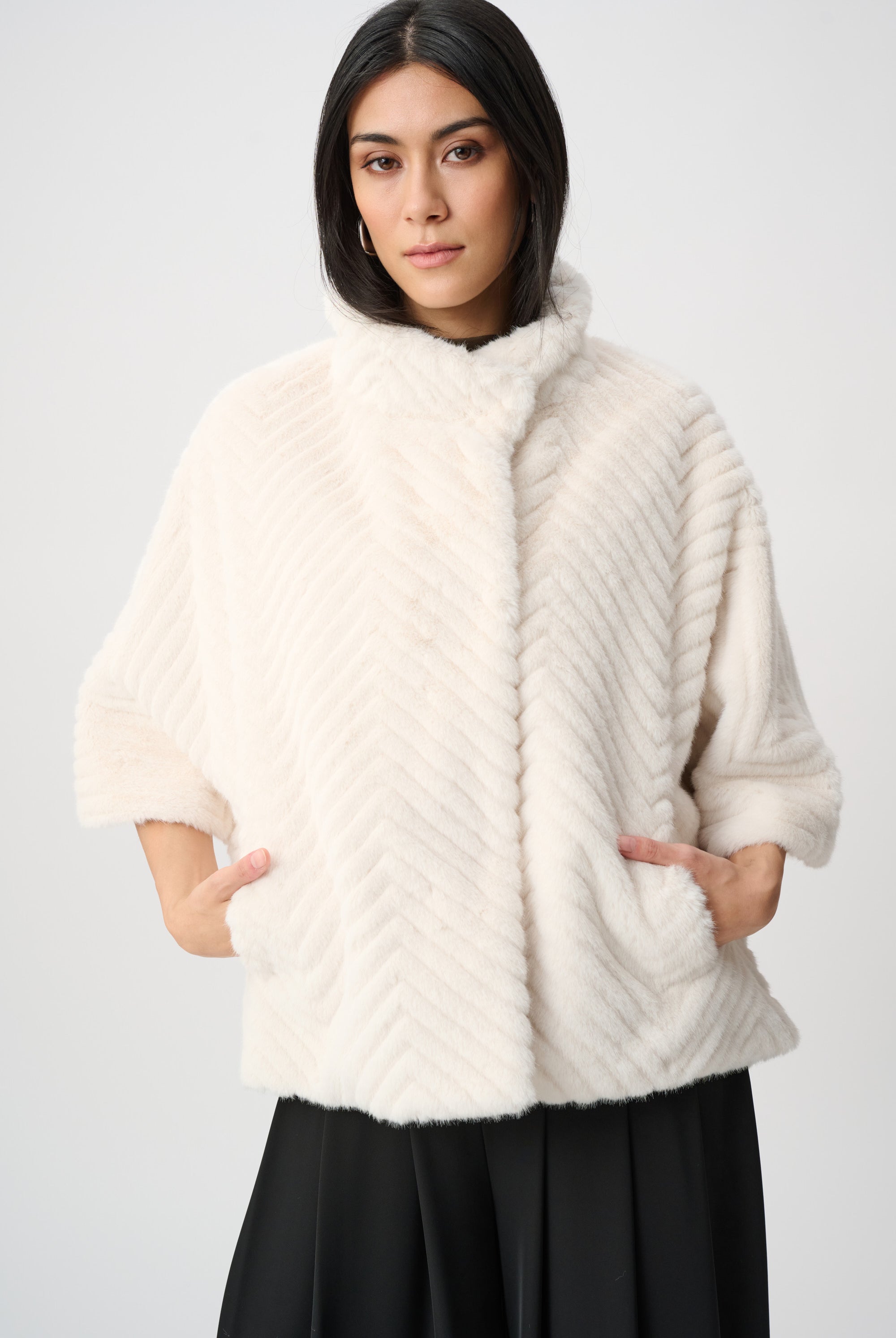 Woman wearing a white fur coat against a plain background
