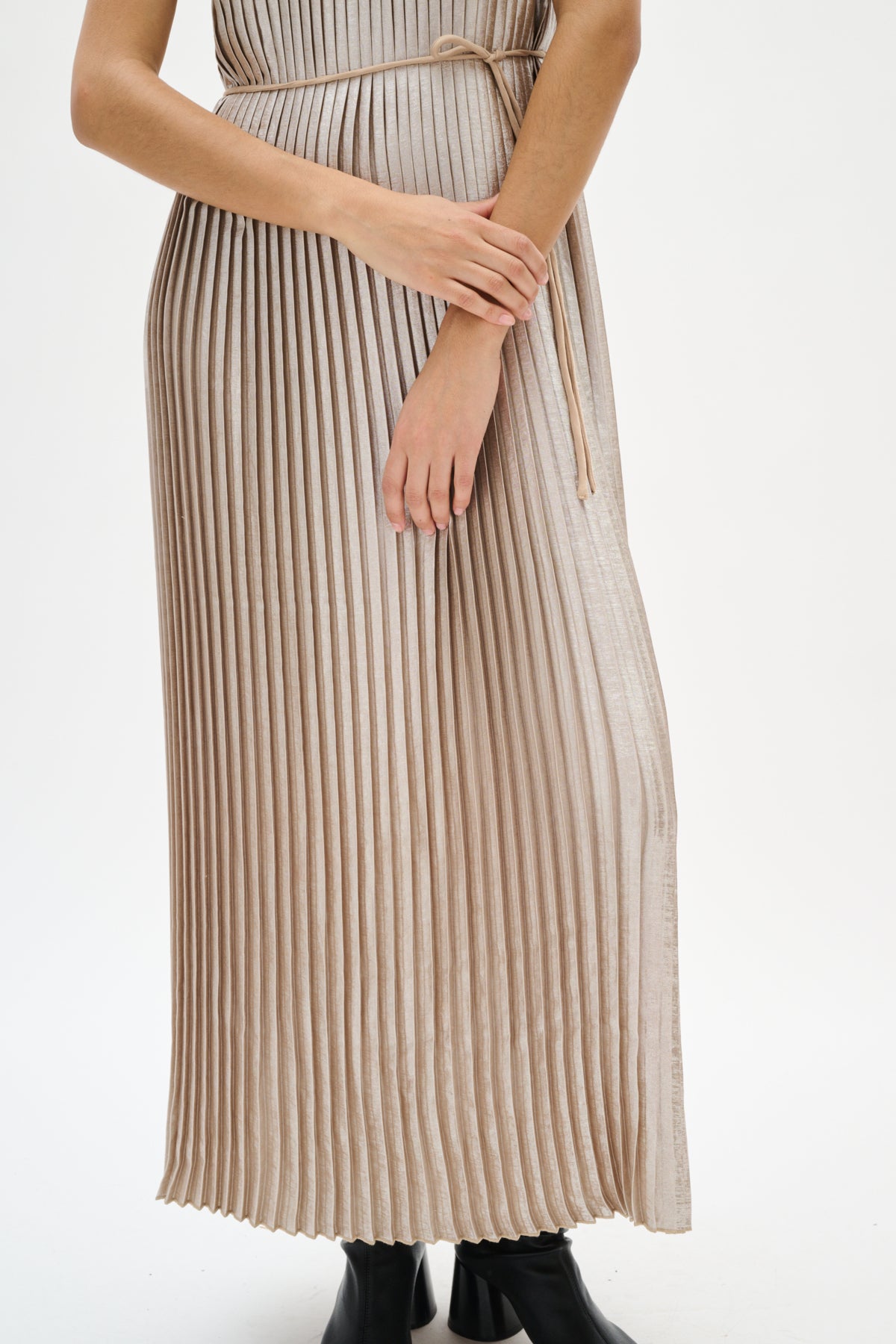 Woman wearing a silver beige pleated dress on a white background close up