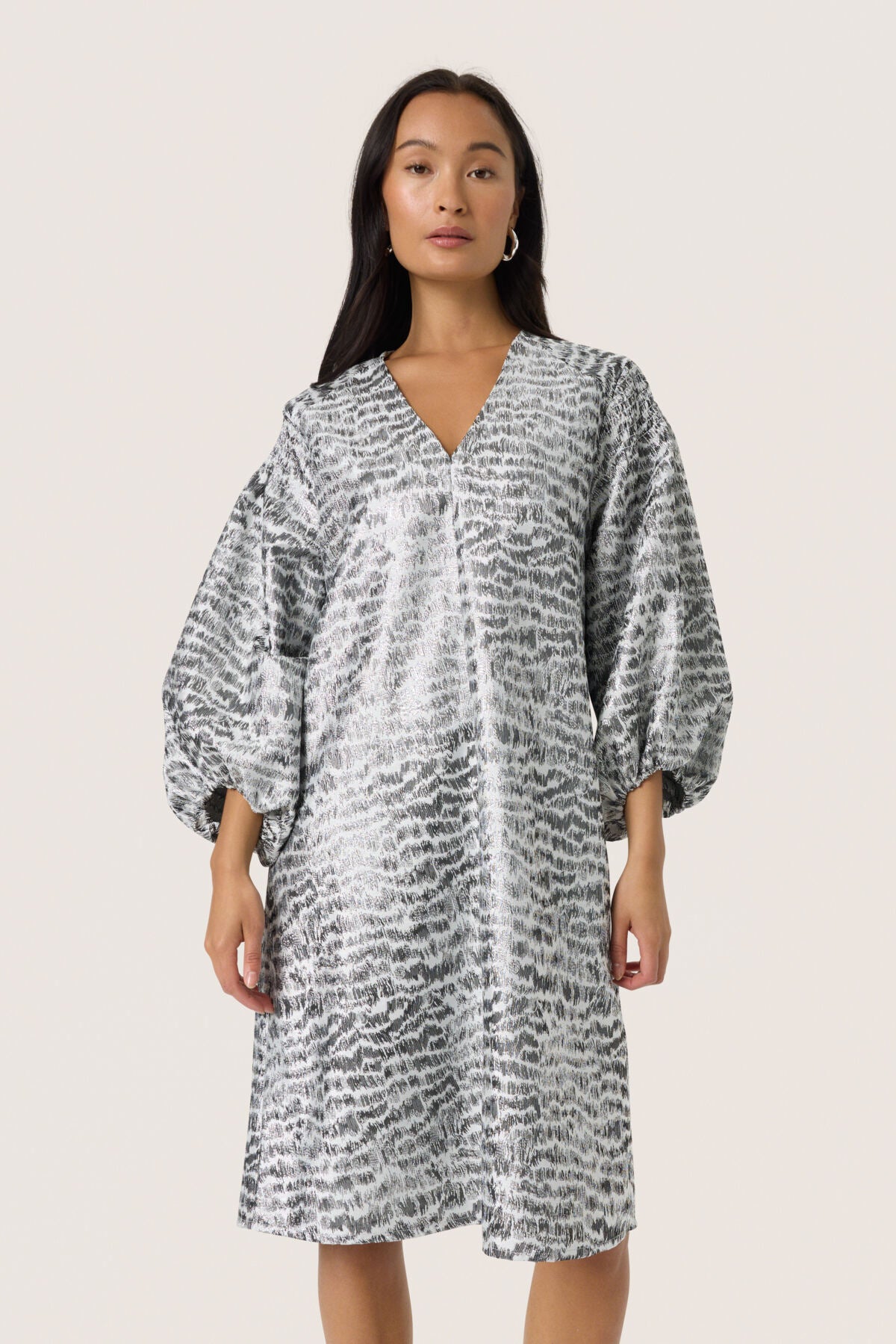 Woman wearing a patterned dress on a plain background