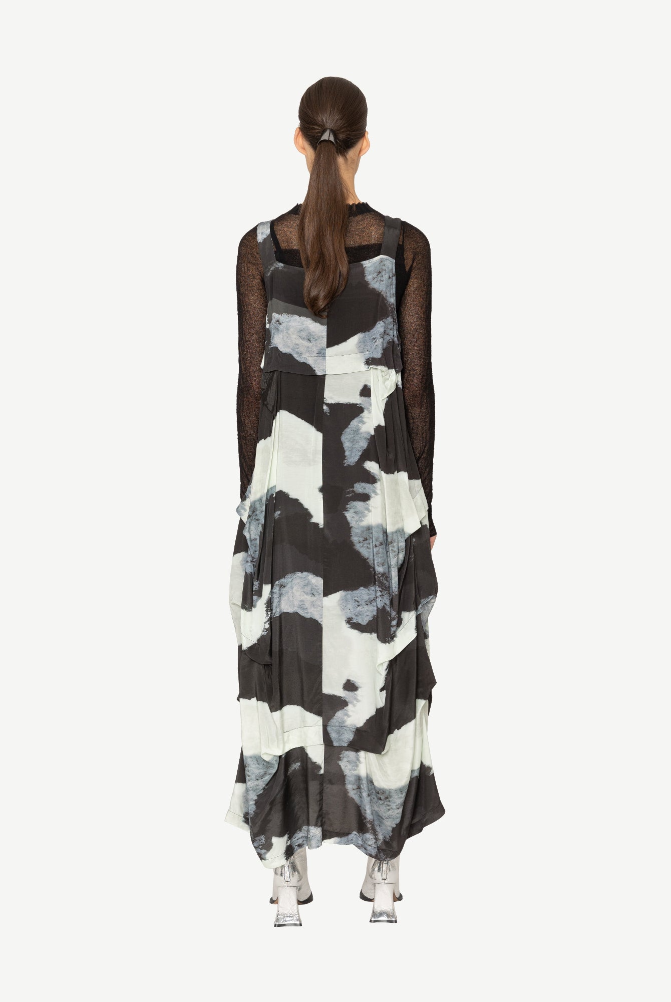 Woman wearing a black and white patterned dress on a white background back angle