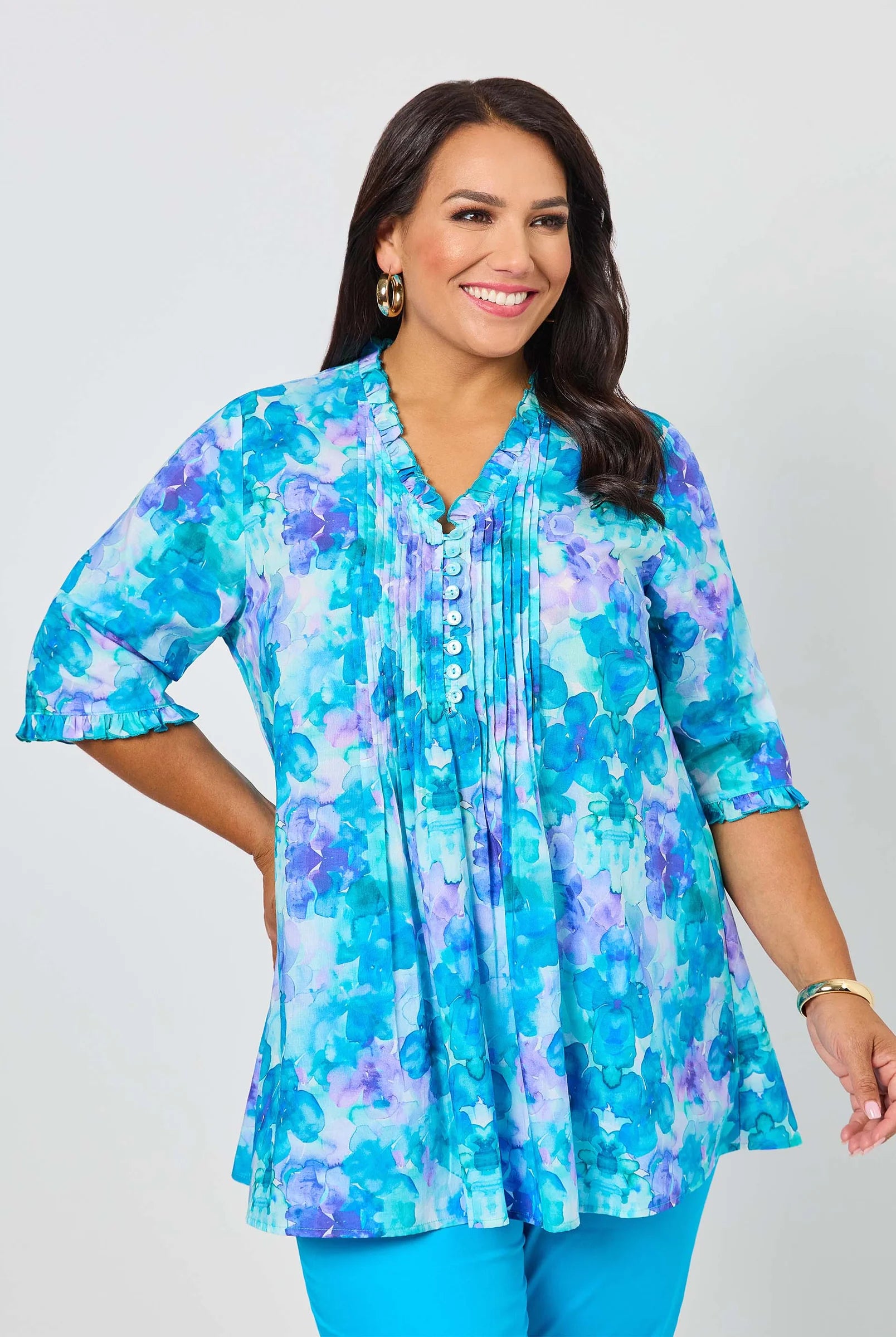 Woman wearing a blue and purple floral blouse against a white background