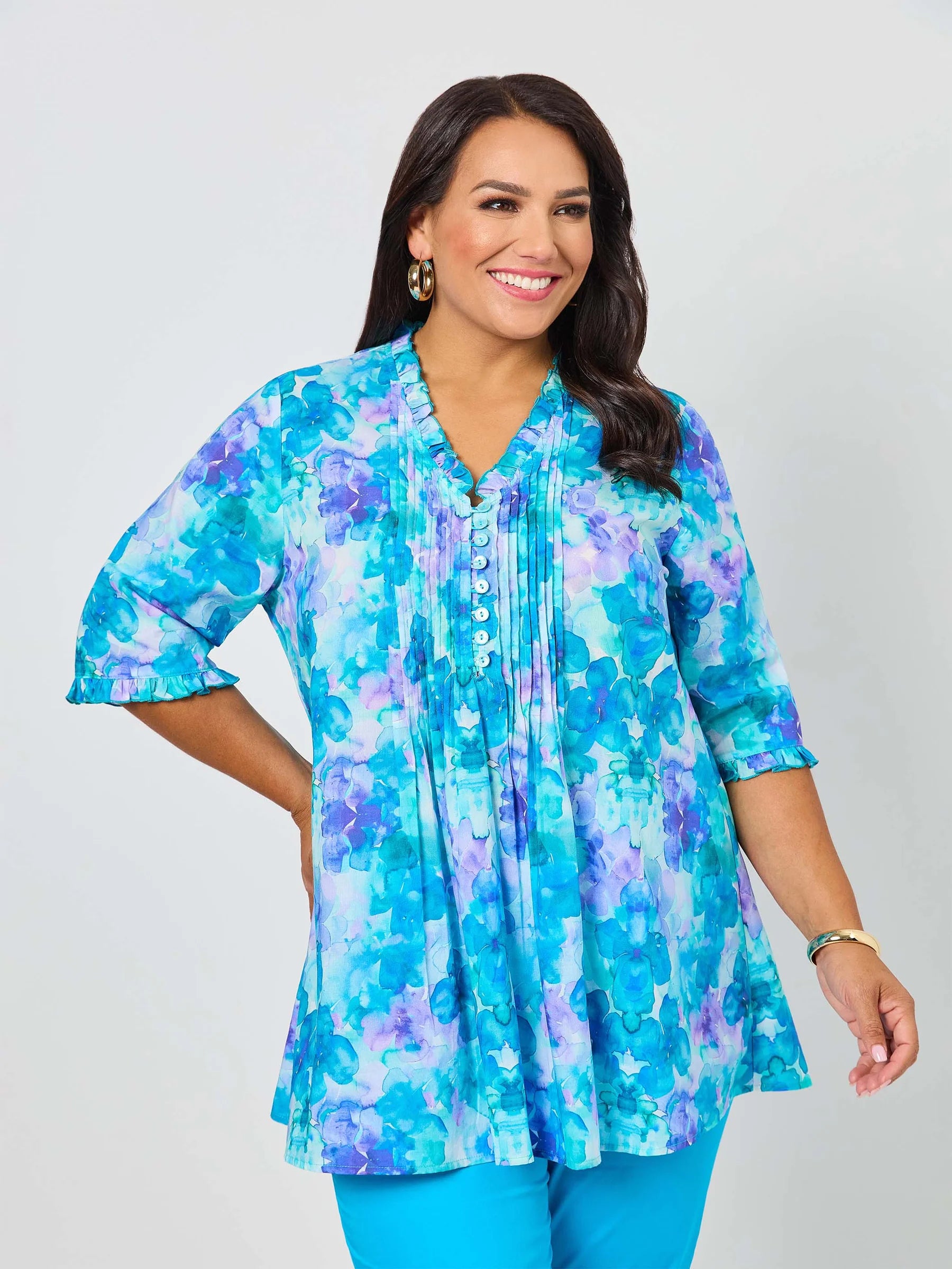 Woman wearing a blue and purple floral blouse against a white background