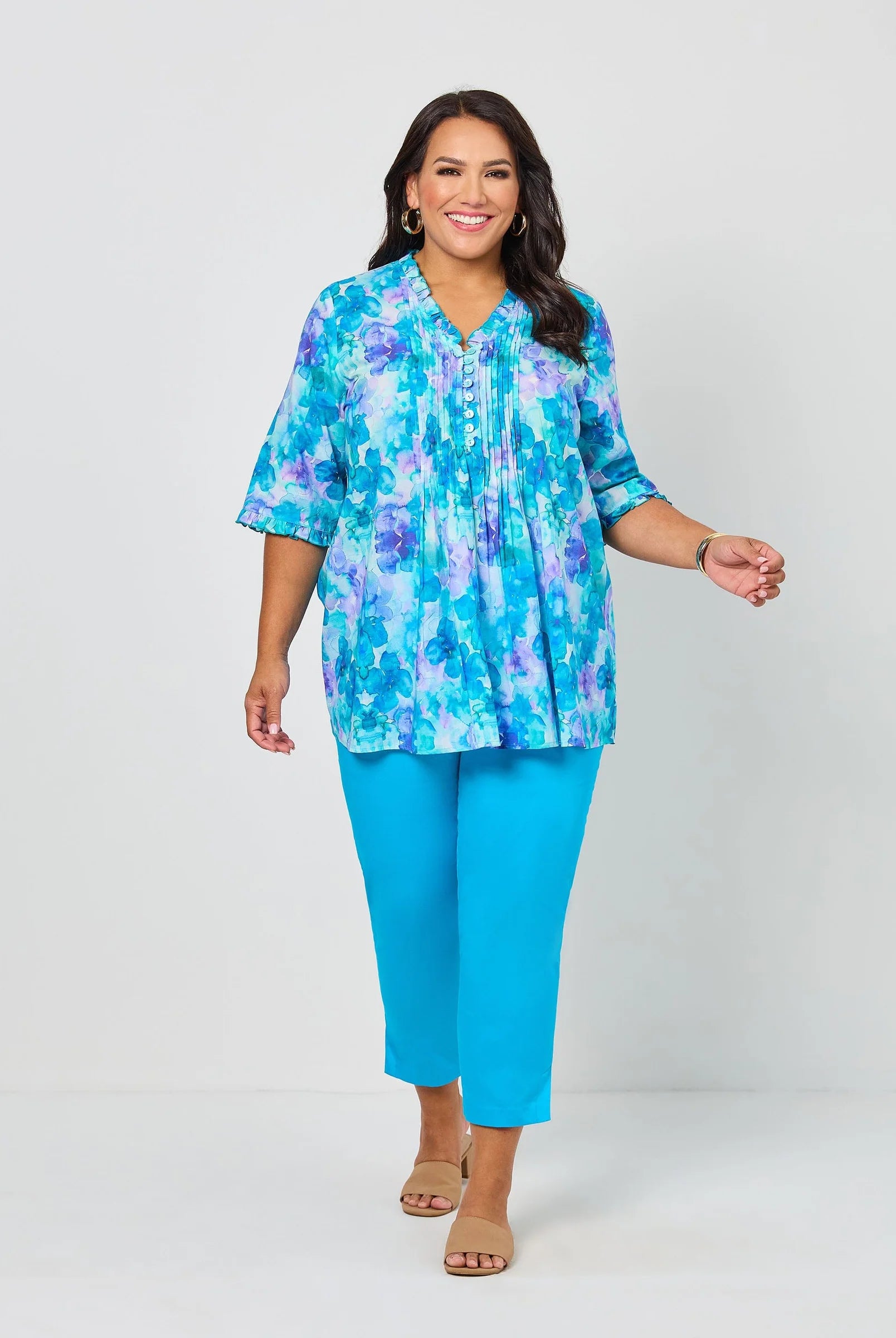 Woman wearing a colorful blouse and blue pants on a white background
