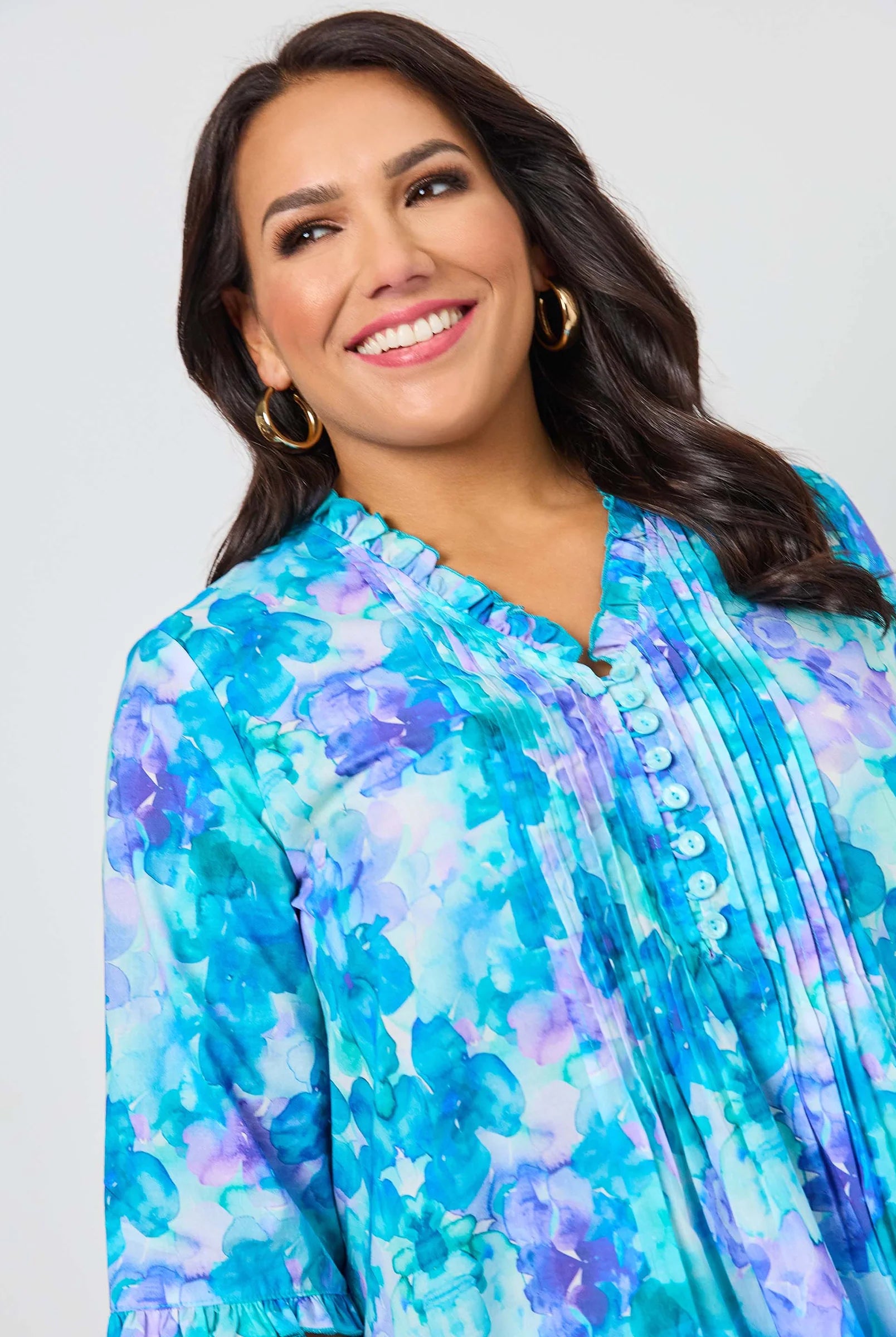 Woman wearing a blue and purple floral blouse against a plain background