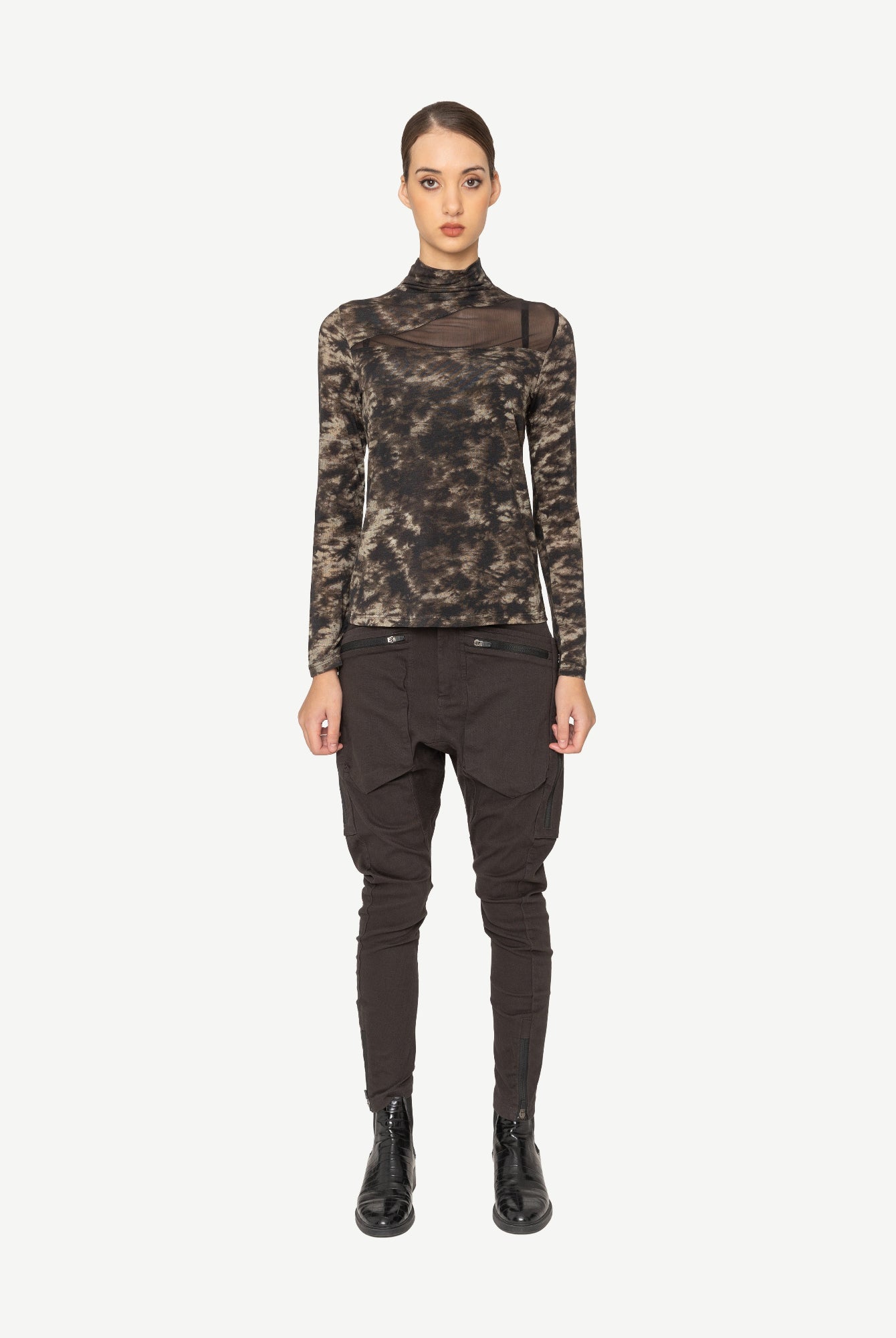 Woman wearing a printed long-sleeve top and black pants on a white background