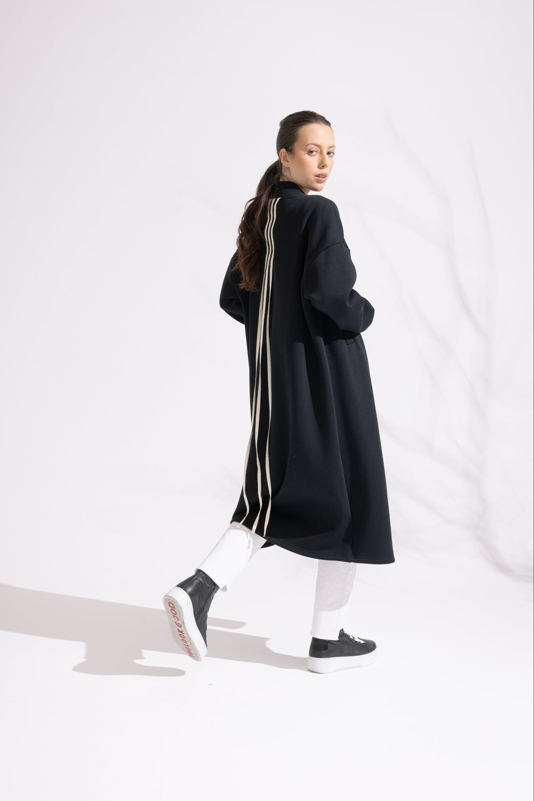Person wearing a long black coat on a white background