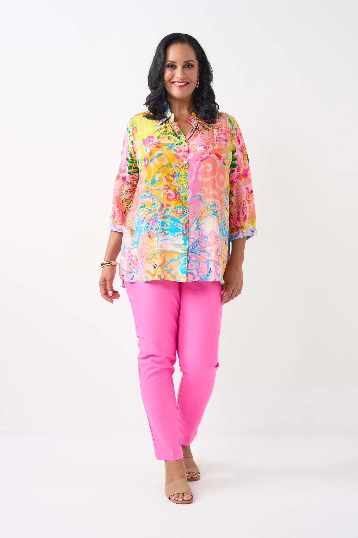 women wearing a patterned shirt and pink pants on a white background