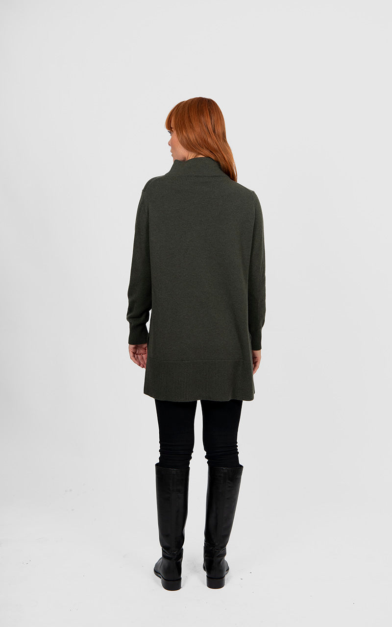 Woman wearing a long dark green coat on a white background