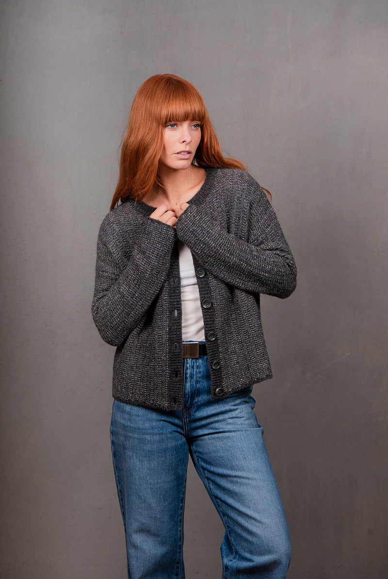 Woman wearing a gray cardigan and blue jeans against a gray background