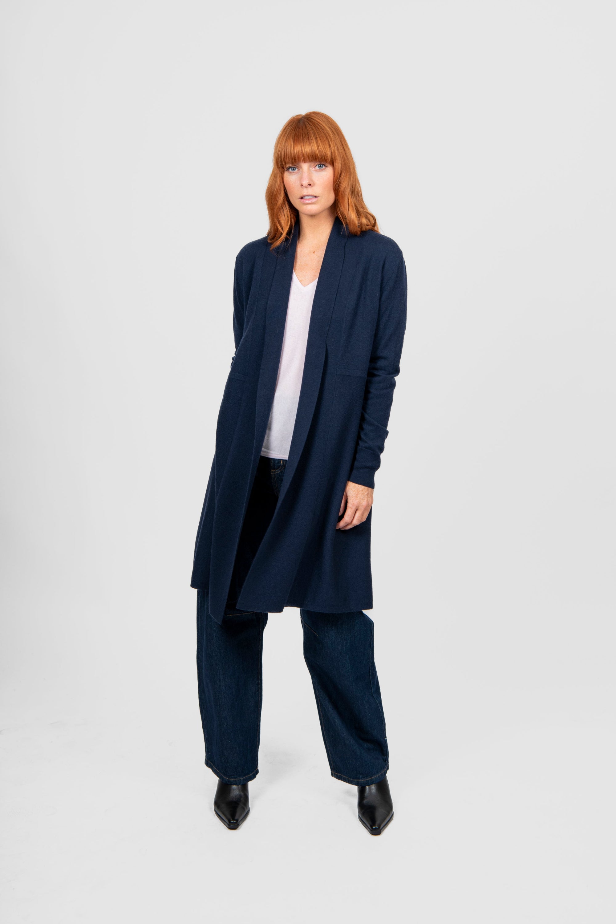 Woman wearing a navy blue cardigan and pants on a white background