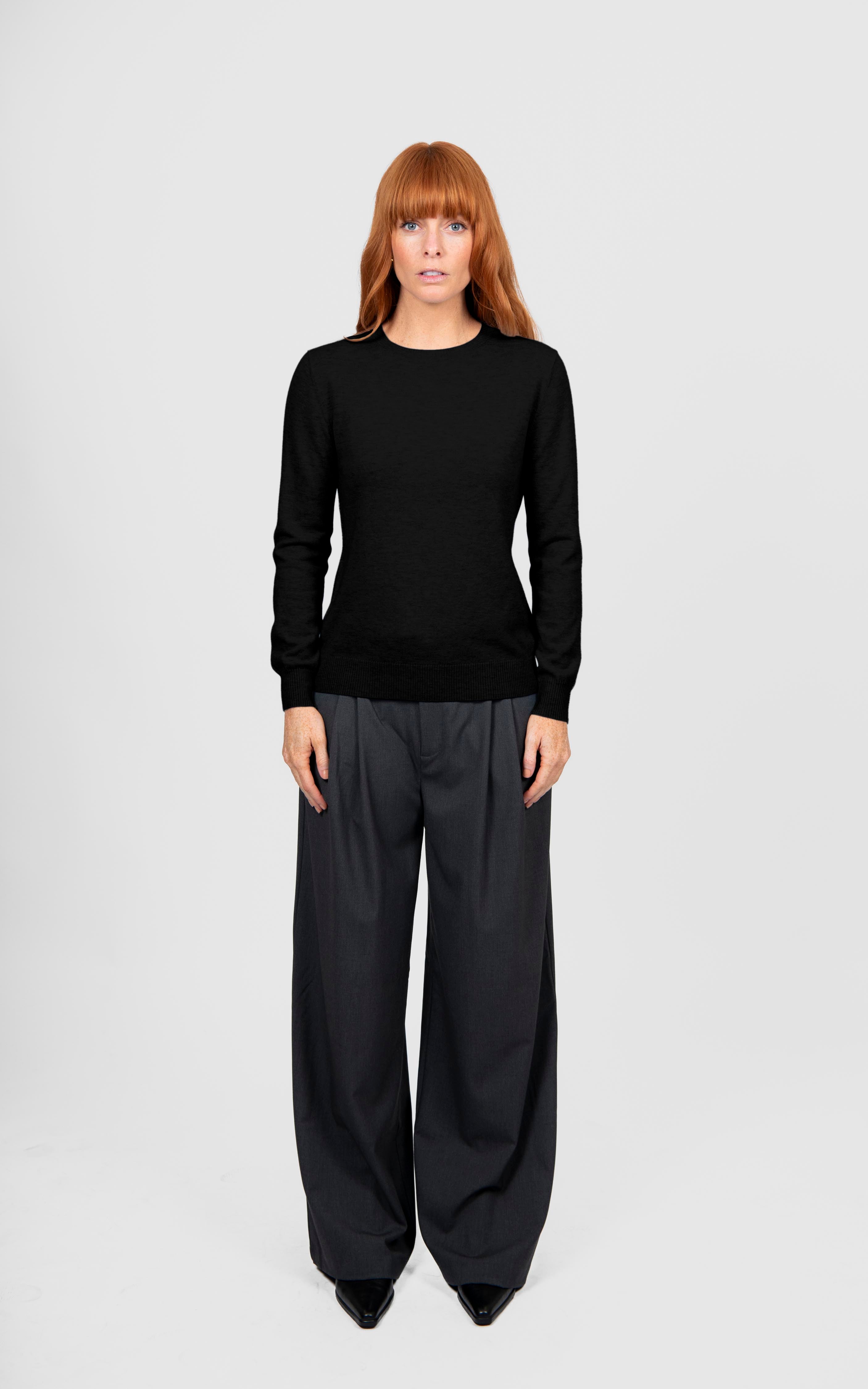Person wearing a black sweater and black pants on a white background