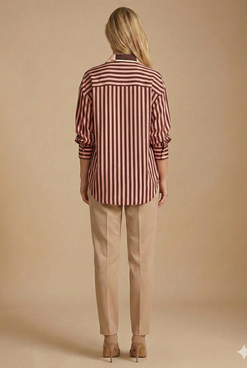 A woman viewed from behind wearing a long-sleeve button-up shirt with vertical burgundy and beige stripes, paired with beige trousers and beige heels, against a solid beige studio background.