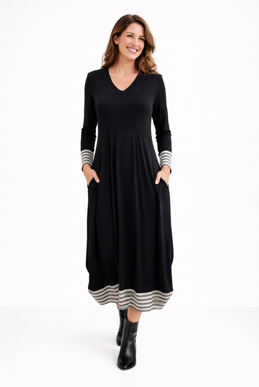 Woman wearing a black dress with striped cuffs and hem on a white background