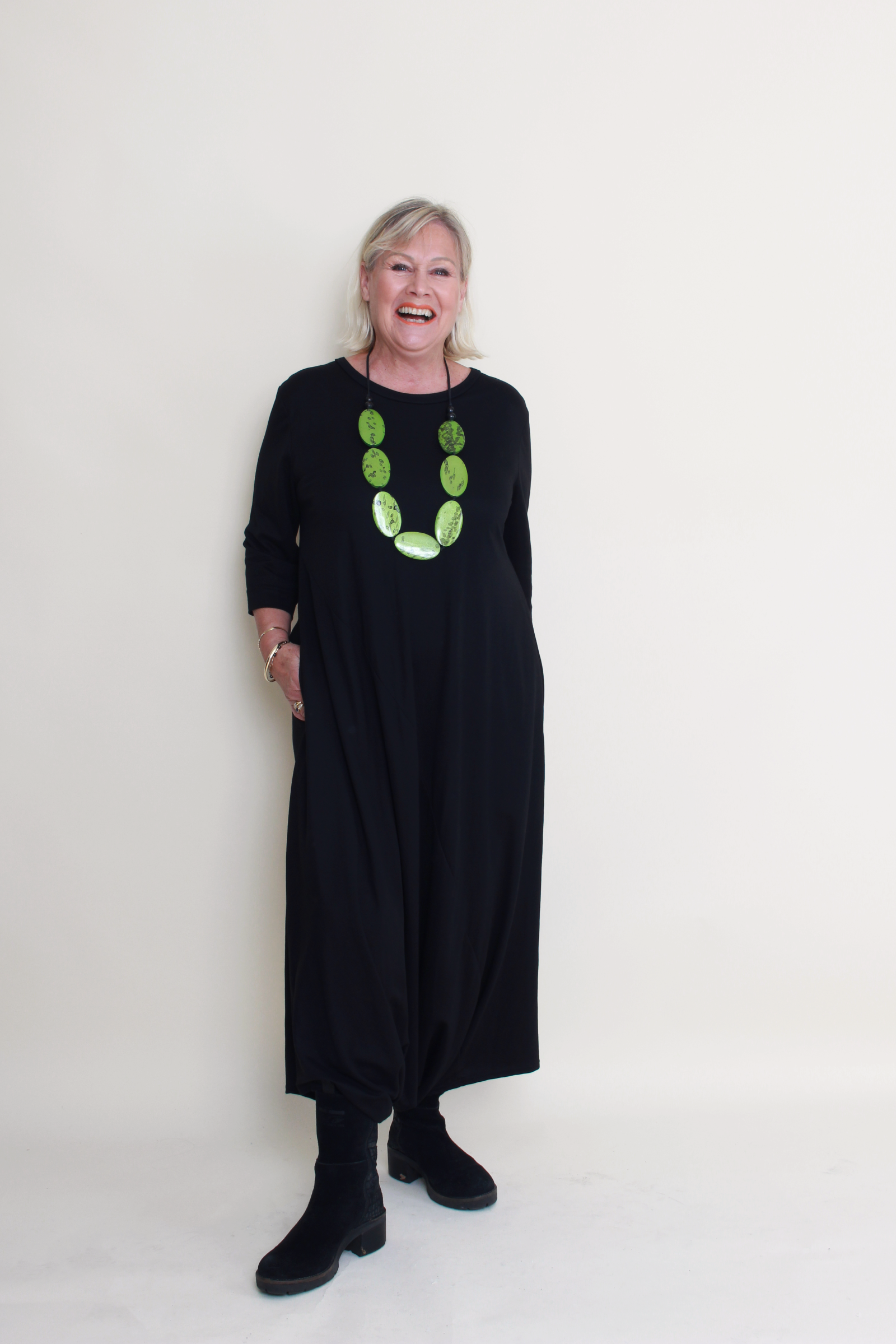 Woman wearing a black dress with a green necklace on a white background