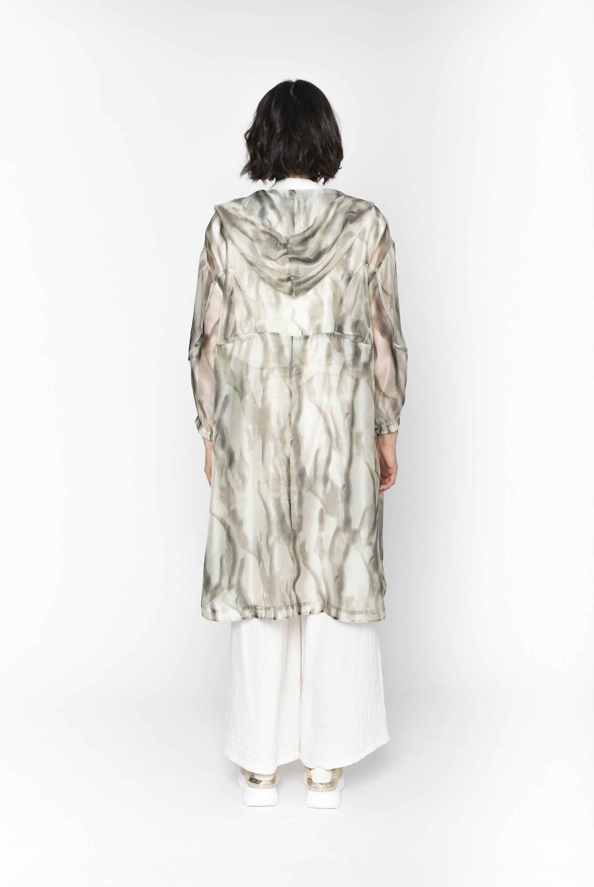 Person wearing a long, patterned coat on a white background