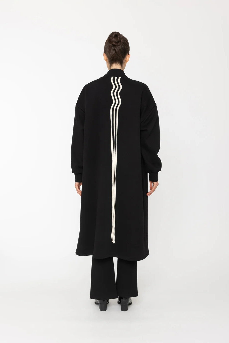Person wearing a black coat with white stripes on a white background