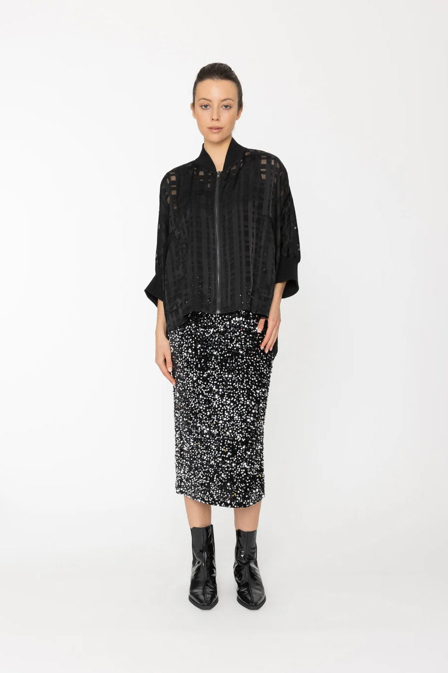 Person wearing a black patterned jacket and skirt on a white background