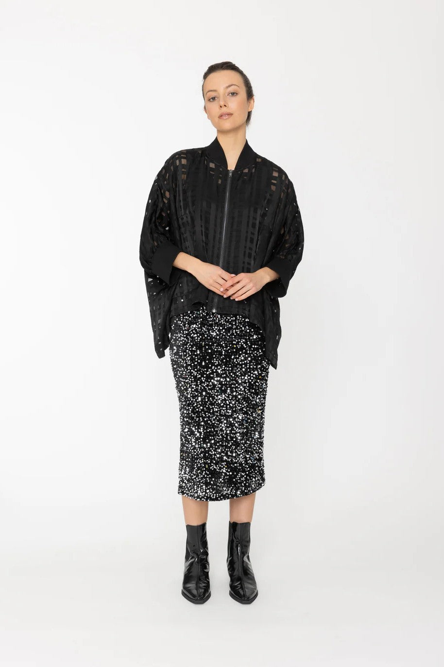 Woman wearing a black lace top and patterned skirt on a white background