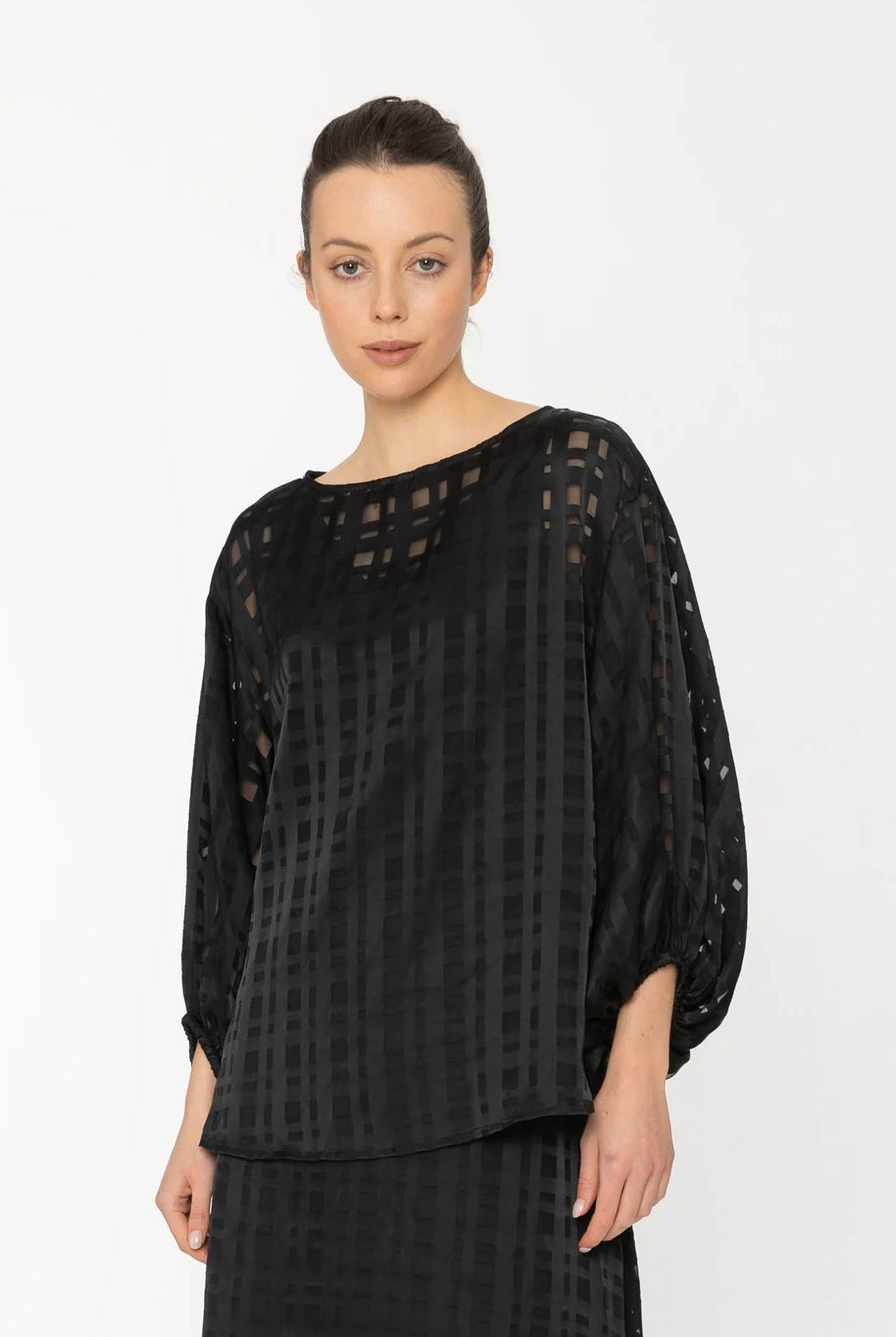 Woman wearing a black sheer blouse with a plain background