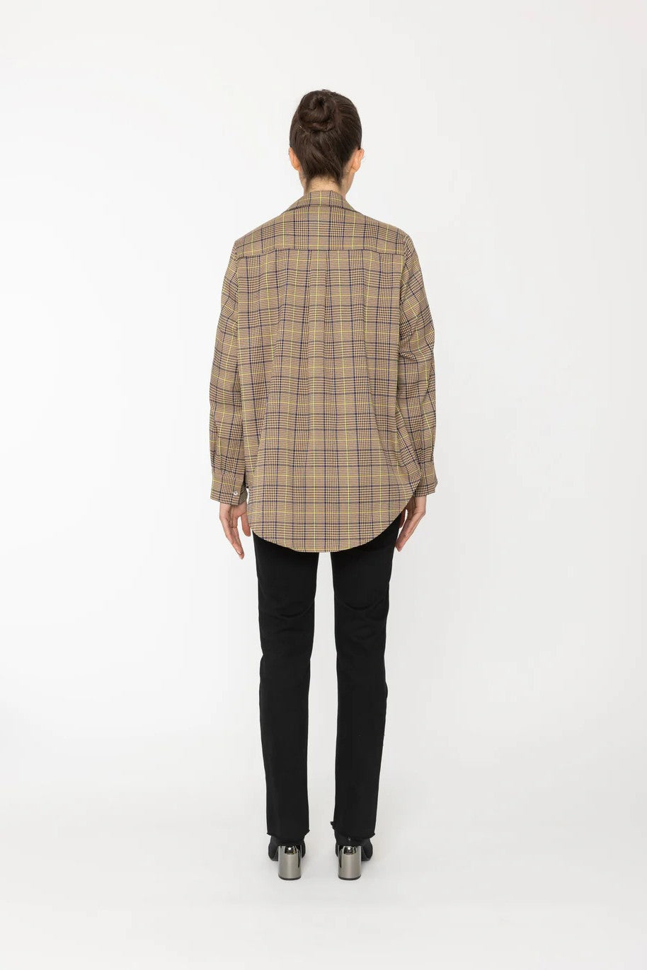 Person wearing a plaid jacket and black pants on a white background back angle