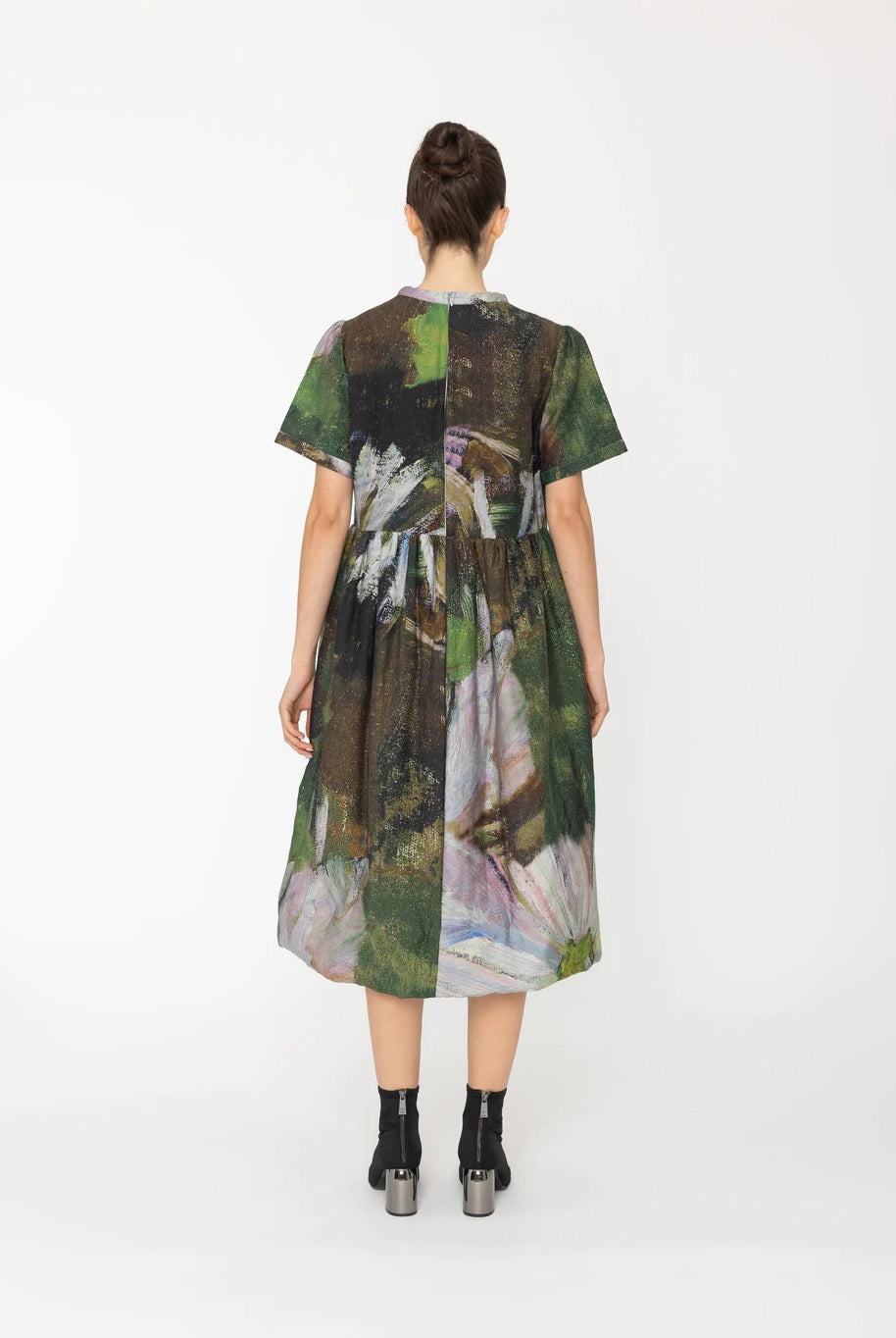 Woman wearing a green abstract patterned dress on a white background back angle