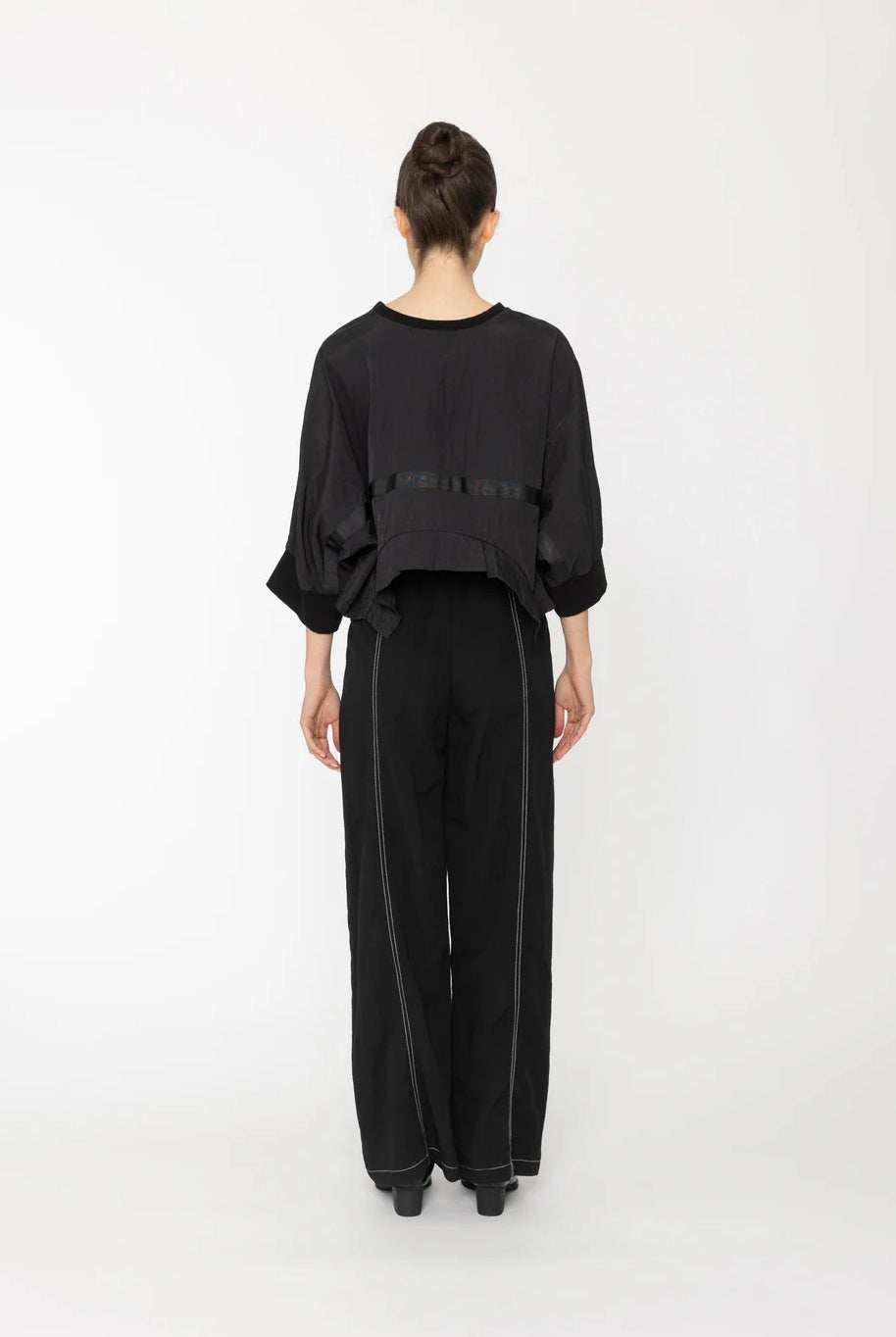 Person wearing a black outfit on a white background back angle