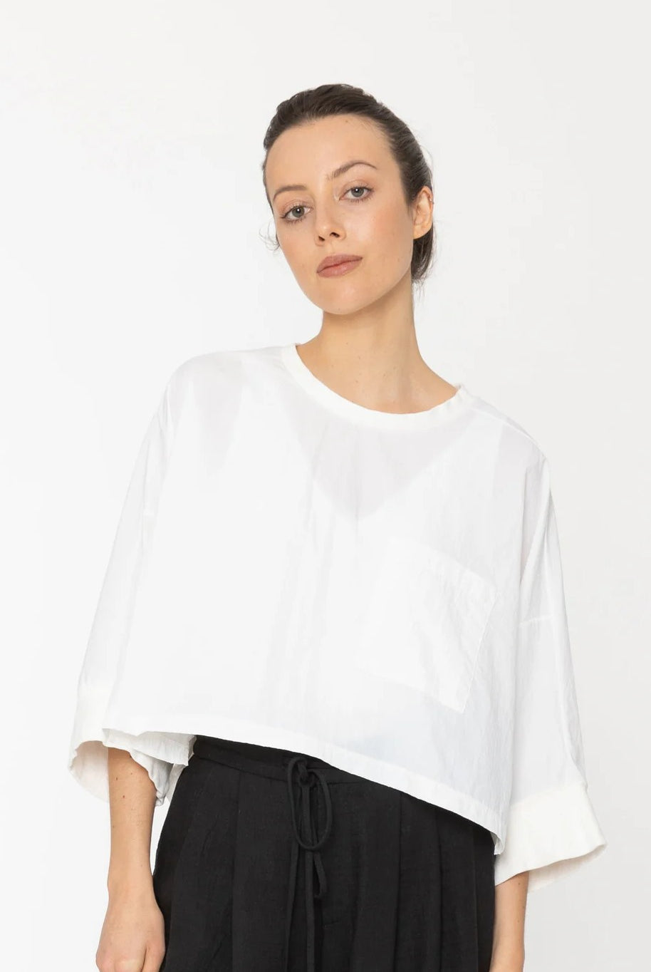 Woman wearing a white blouse and black pants on a white background
