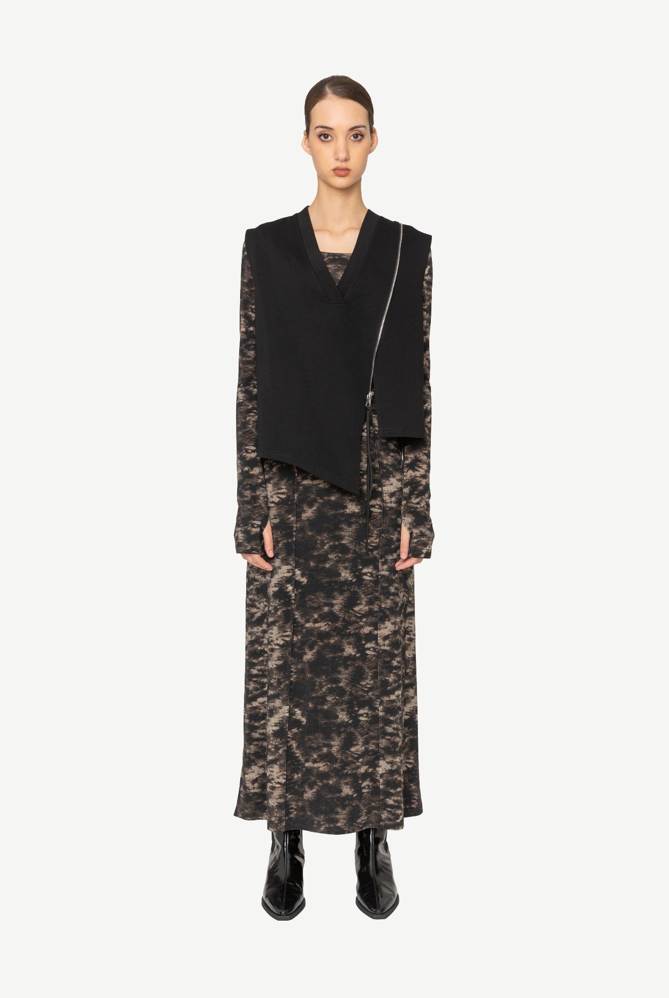 Model wearing black asymmetrical vest over patterned dress