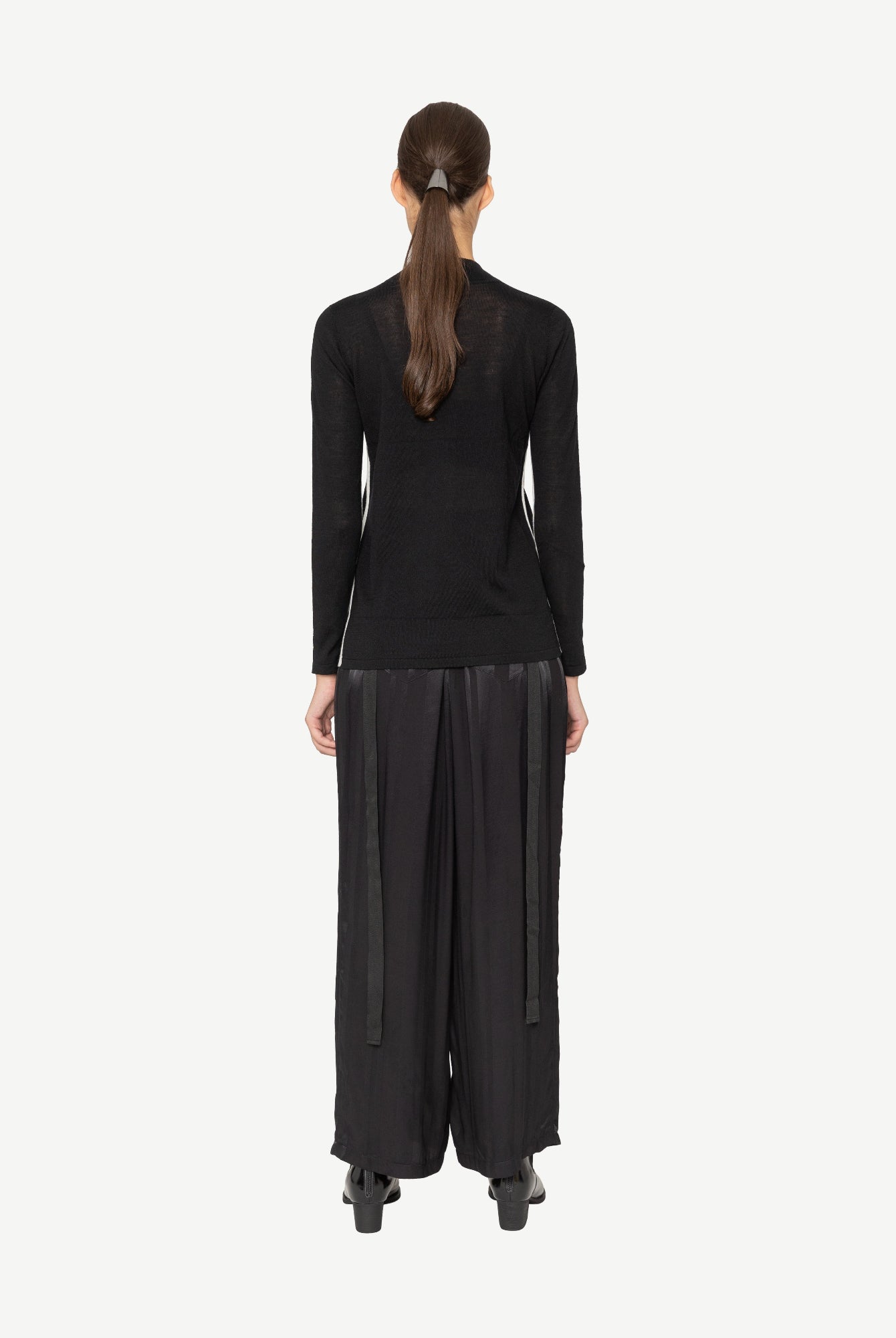 Person wearing a black outfit on a white background back angle