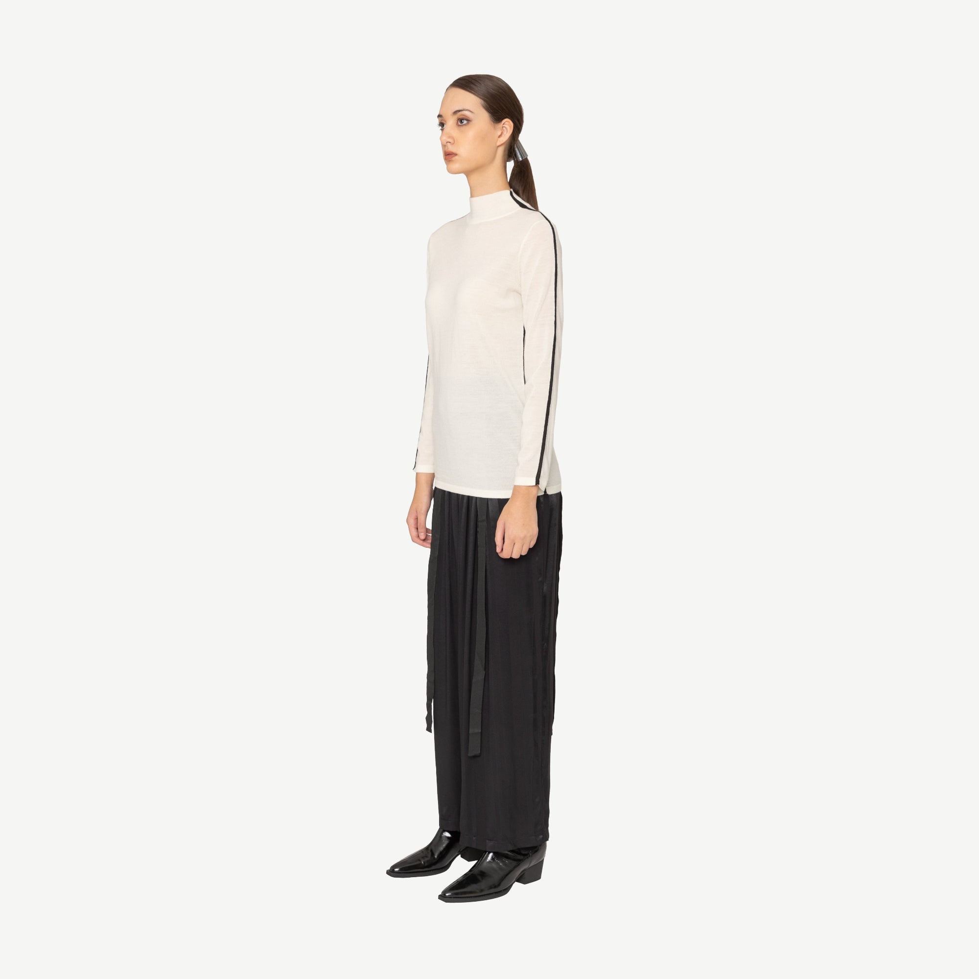 Woman wearing a white top and black pants on a white background