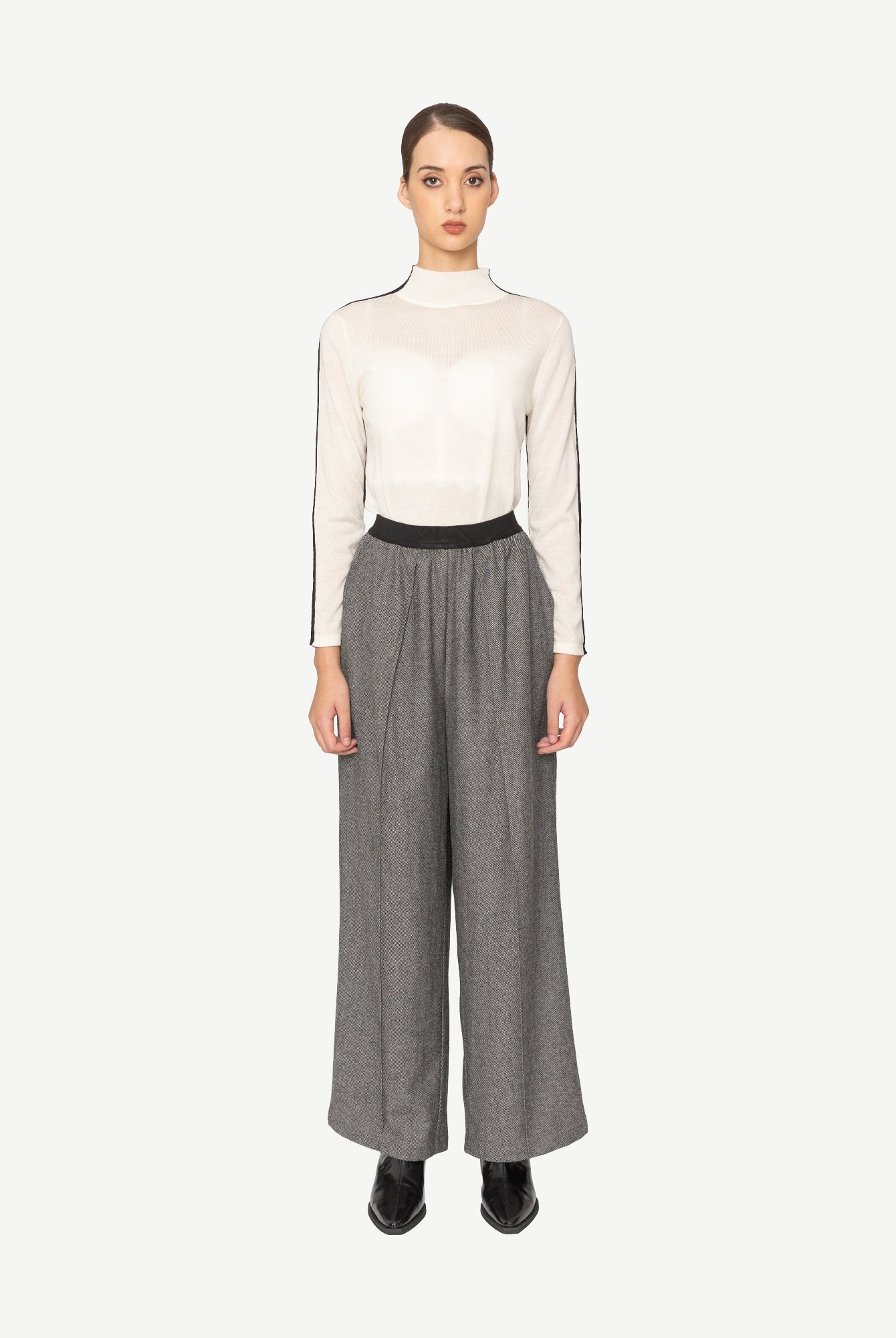 Woman wearing a white top and gray wide-leg pants on a white background