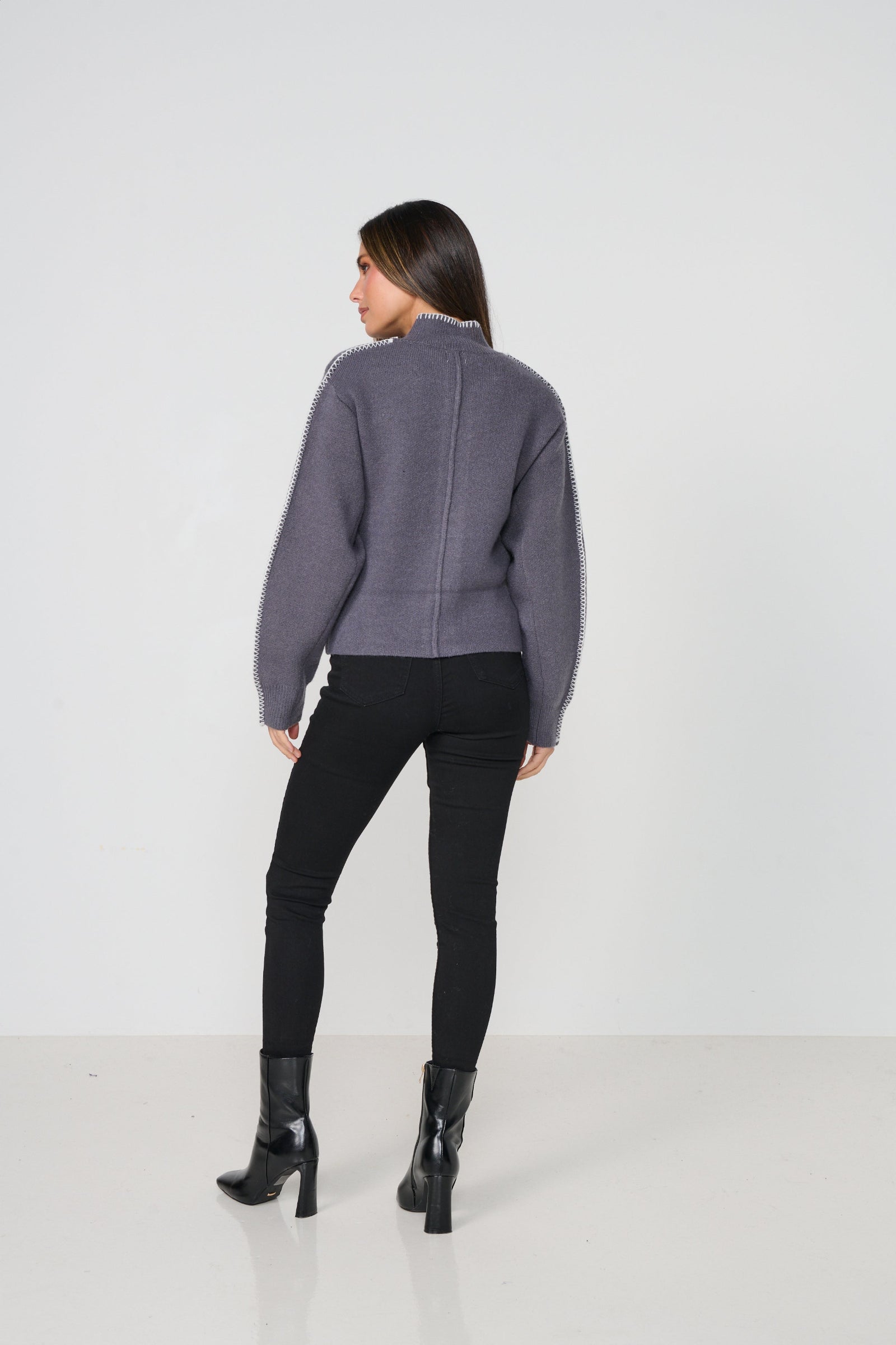 Woman wearing a cardigan and black pants on a white background