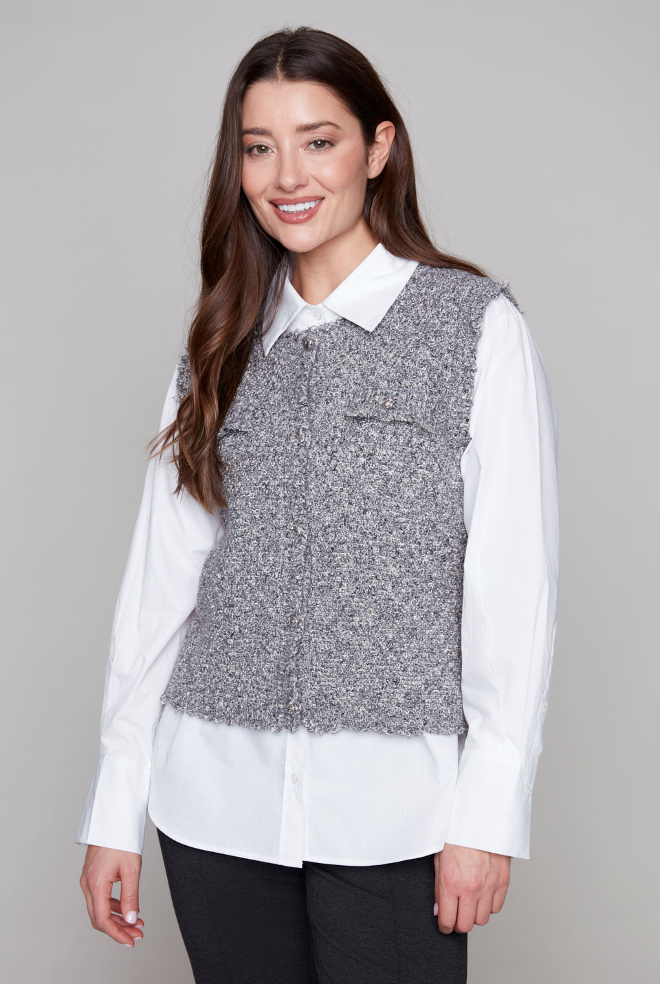 Woman wearing a gray vest over a white shirt on a gray background