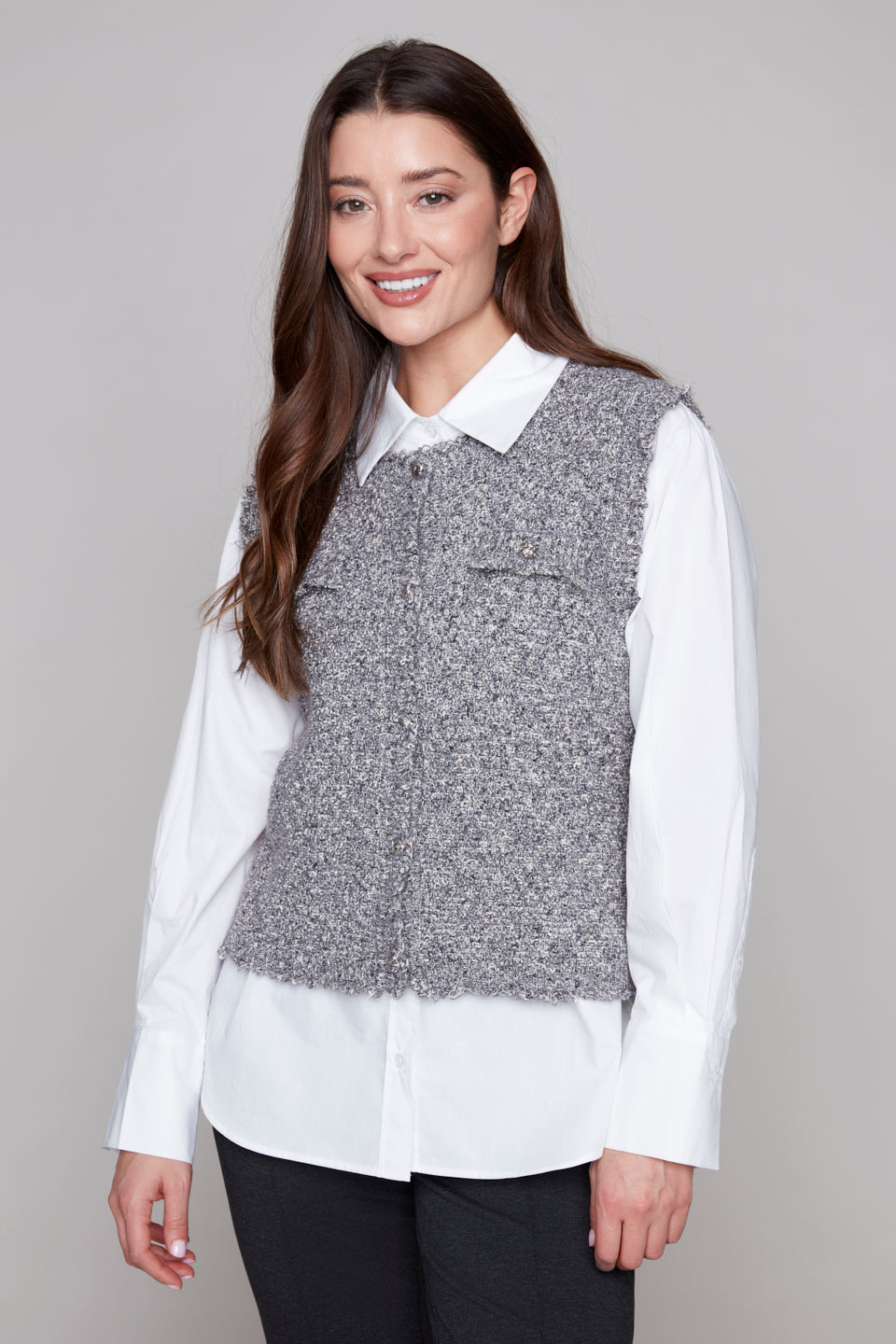 Woman wearing a gray vest over a white shirt on a gray background
