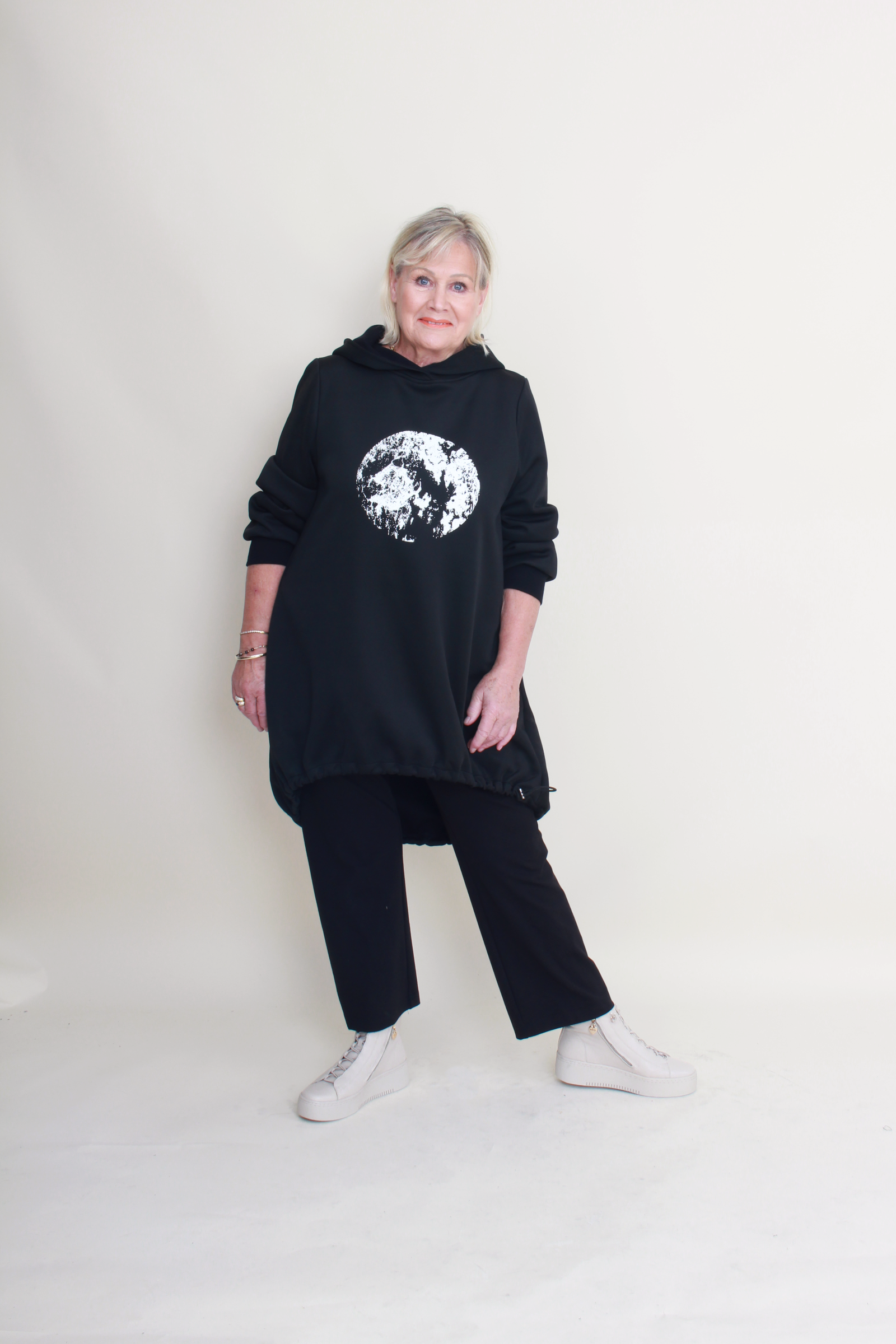 Person wearing a black hoodie with a graphic design on a plain background