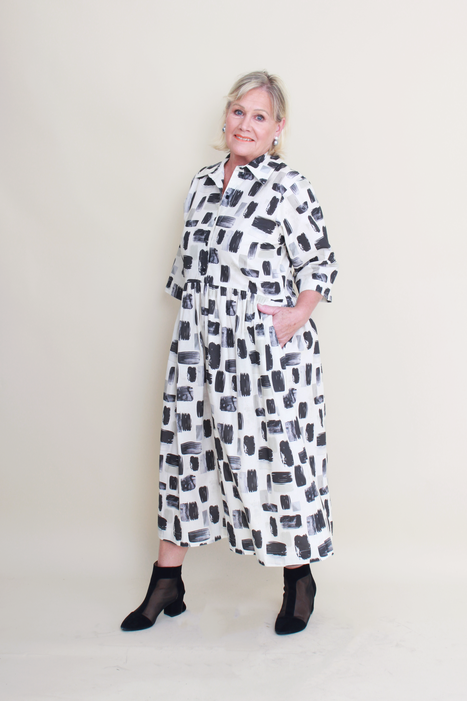 women wearing a cream dress with black and charcoal patterns on a plain background