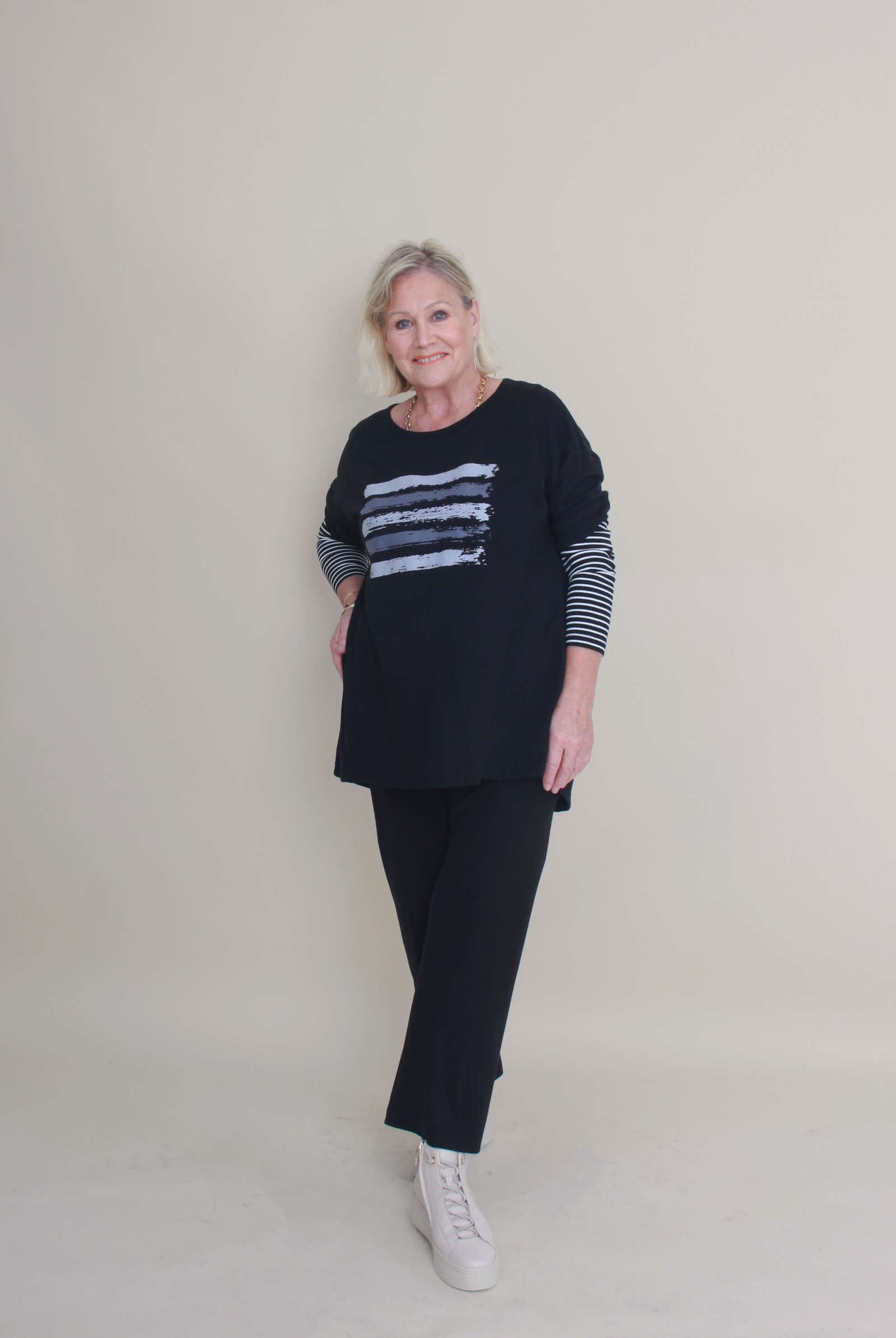 women wearing black pants and a black top with stripes on a plain background