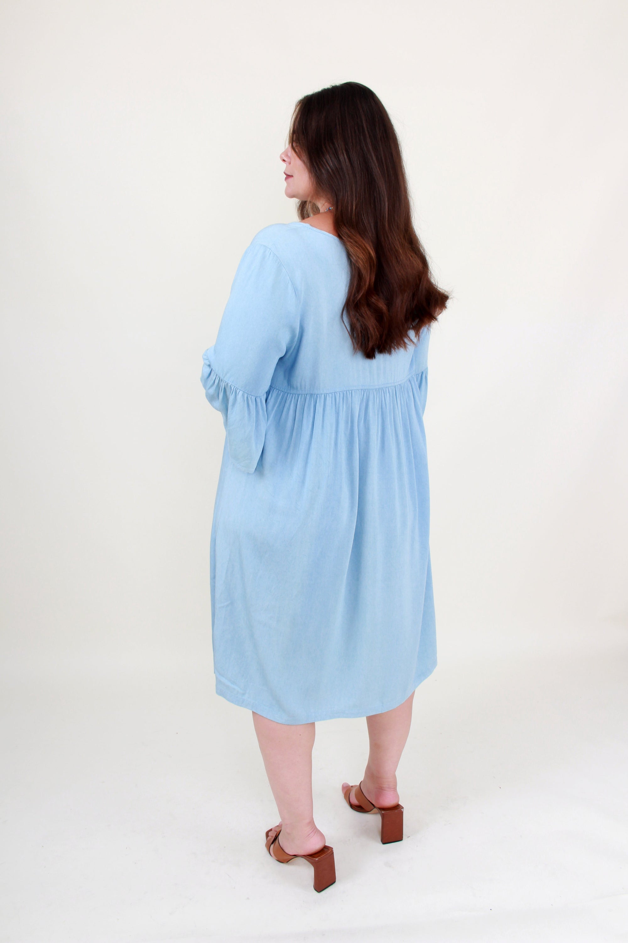 Woman wearing a light blue dress on a white background back view