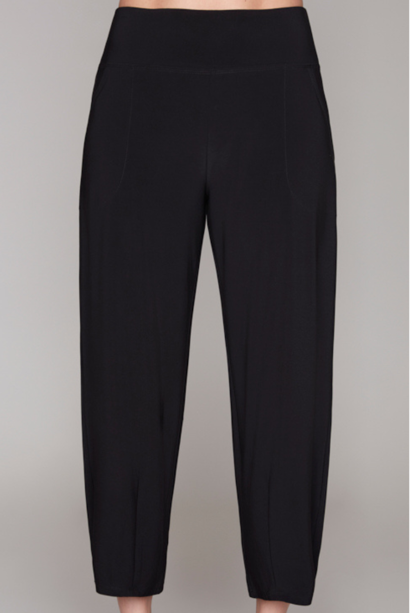 Black cropped pants with a wide waistband, modeled with black strappy high-heeled sandals against a solid gray background.