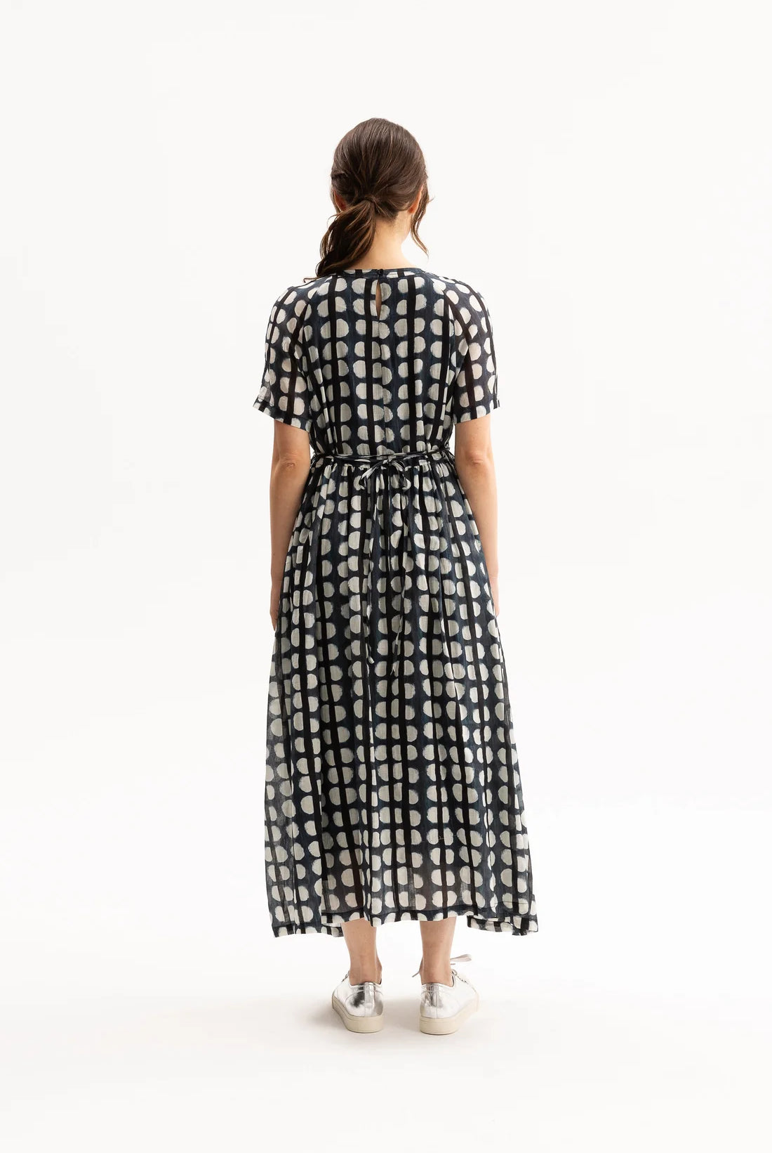 Woman wearing a black, blue, and white patterned dress on a white background