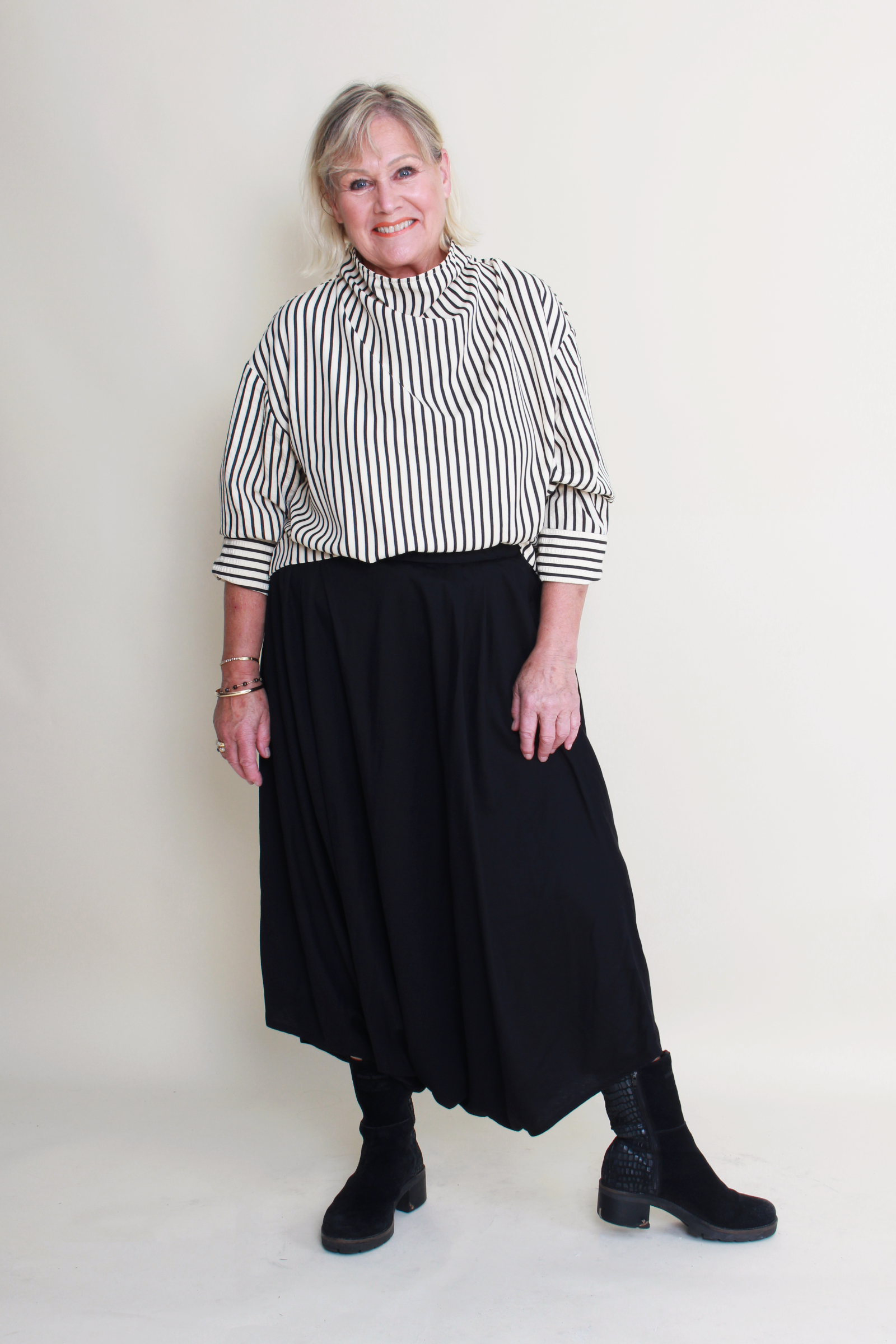 Woman wearing a black and white striped shirt with a black skirt on a white background