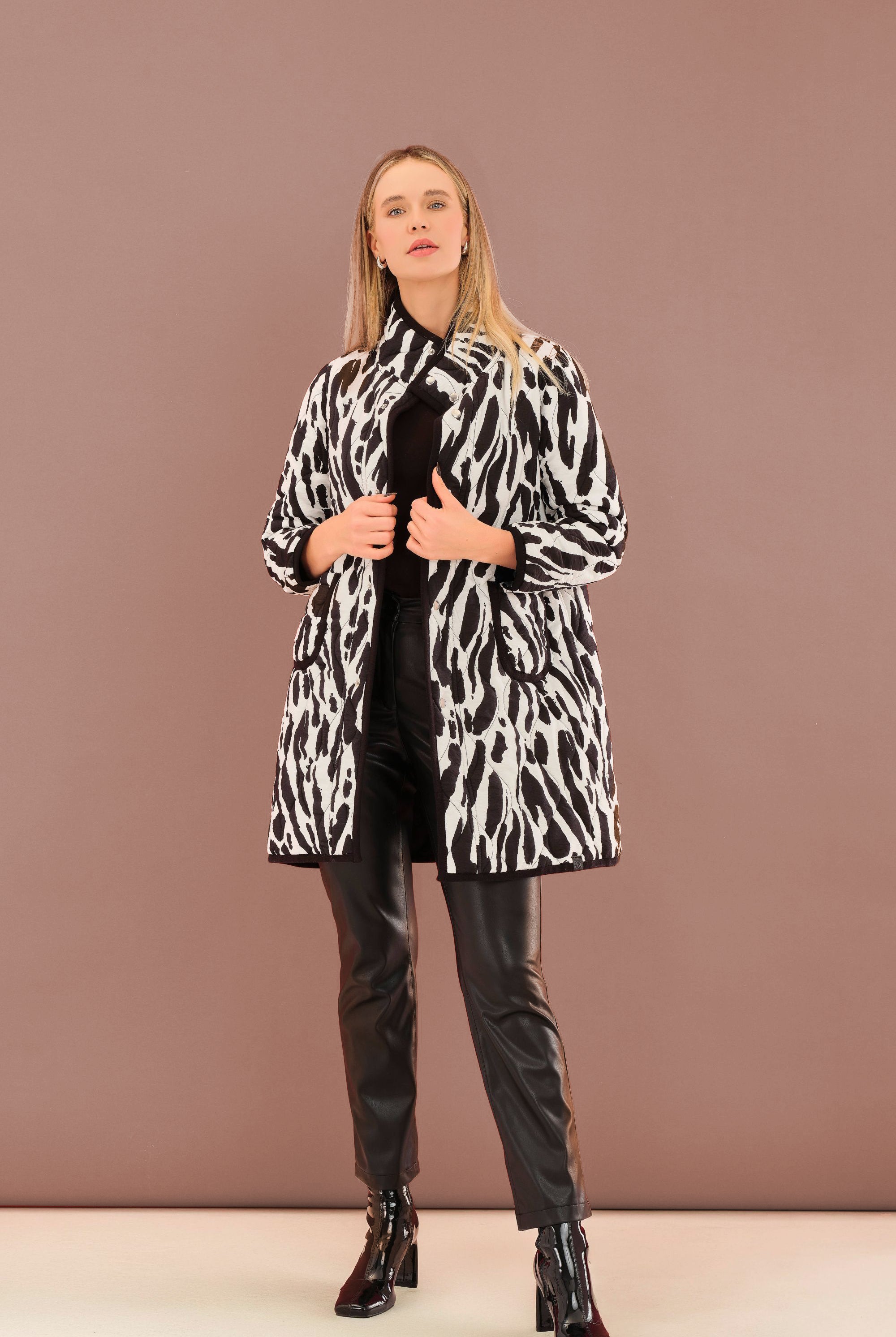 Woman wearing a black and white patterned coat against a brown background
