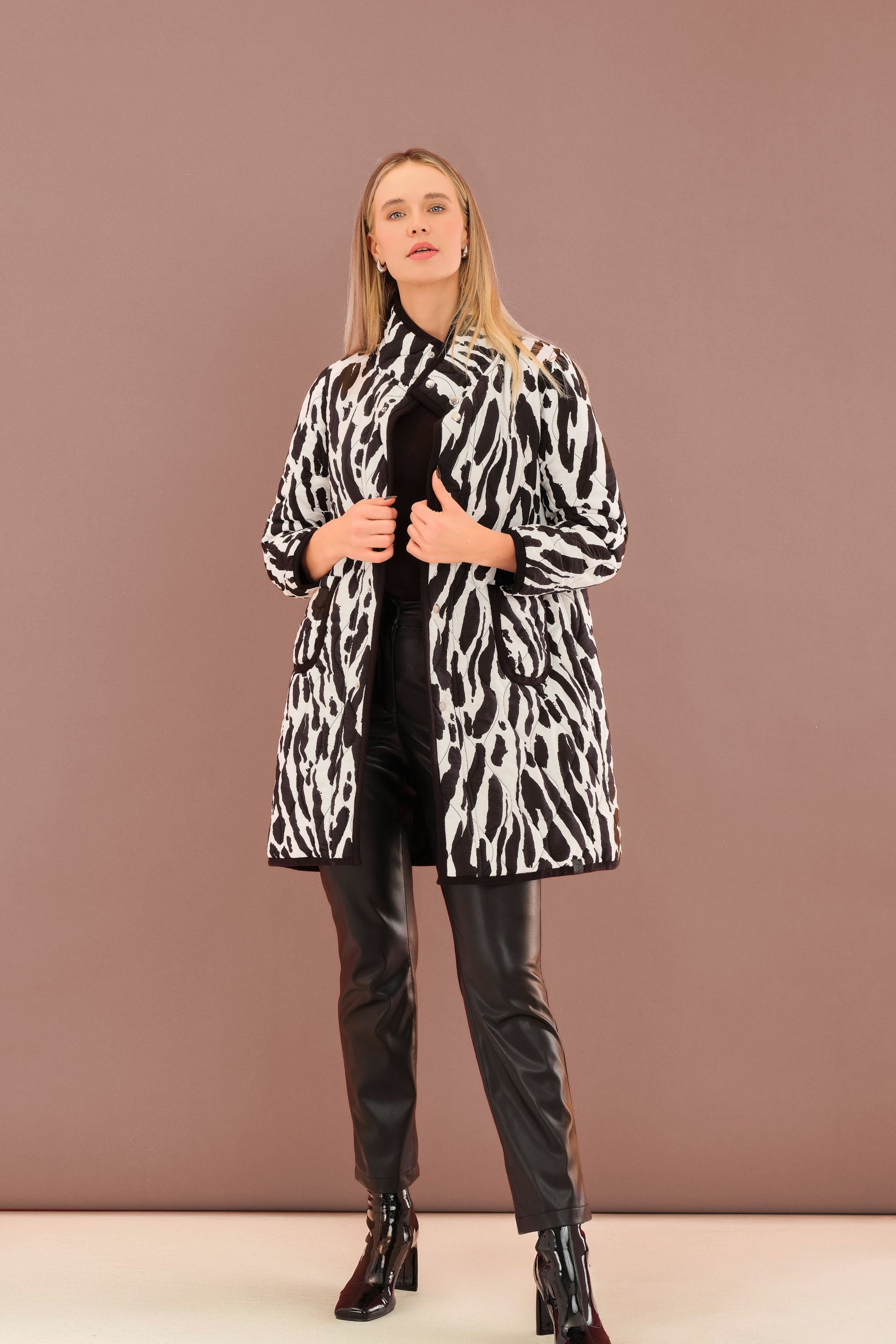 Woman wearing a black and white patterned coat against a brown background