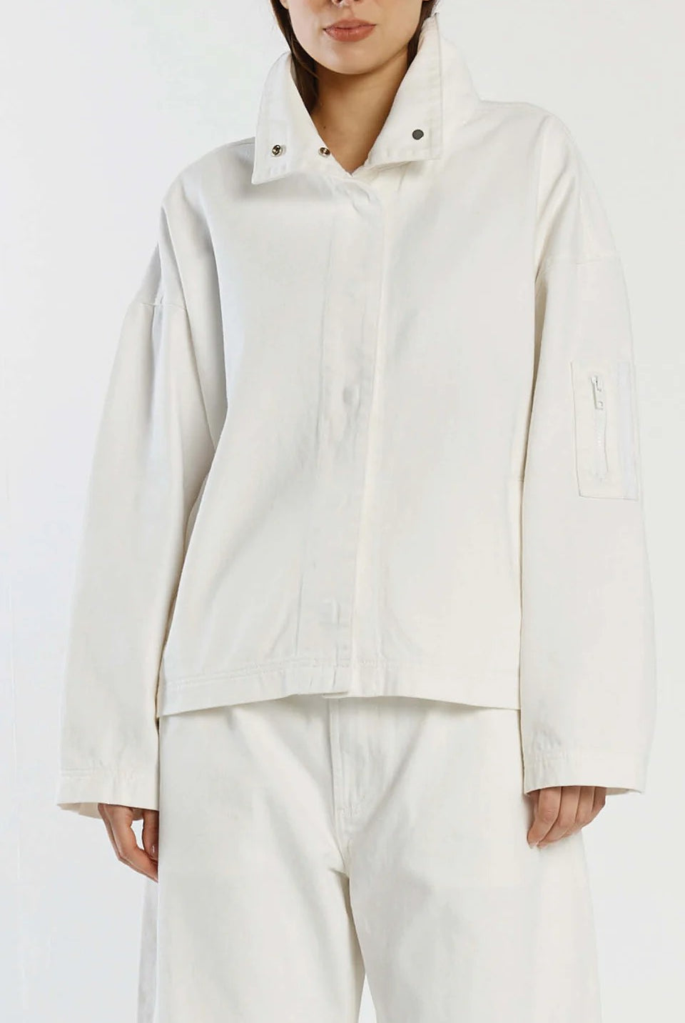 Person wearing a light-colored jacket and pants on a white background